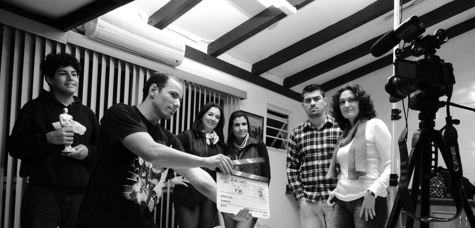 Un groupe de personnes rassemblées autour d'un dispositif de caméra dans un studio, avec un clap de cinéma au premier plan.