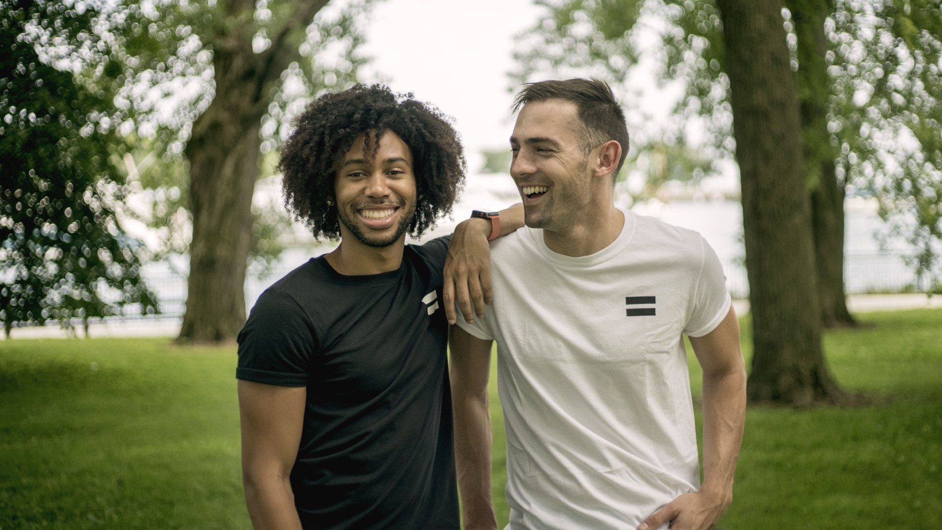 Two men are standing next to each other in a park.