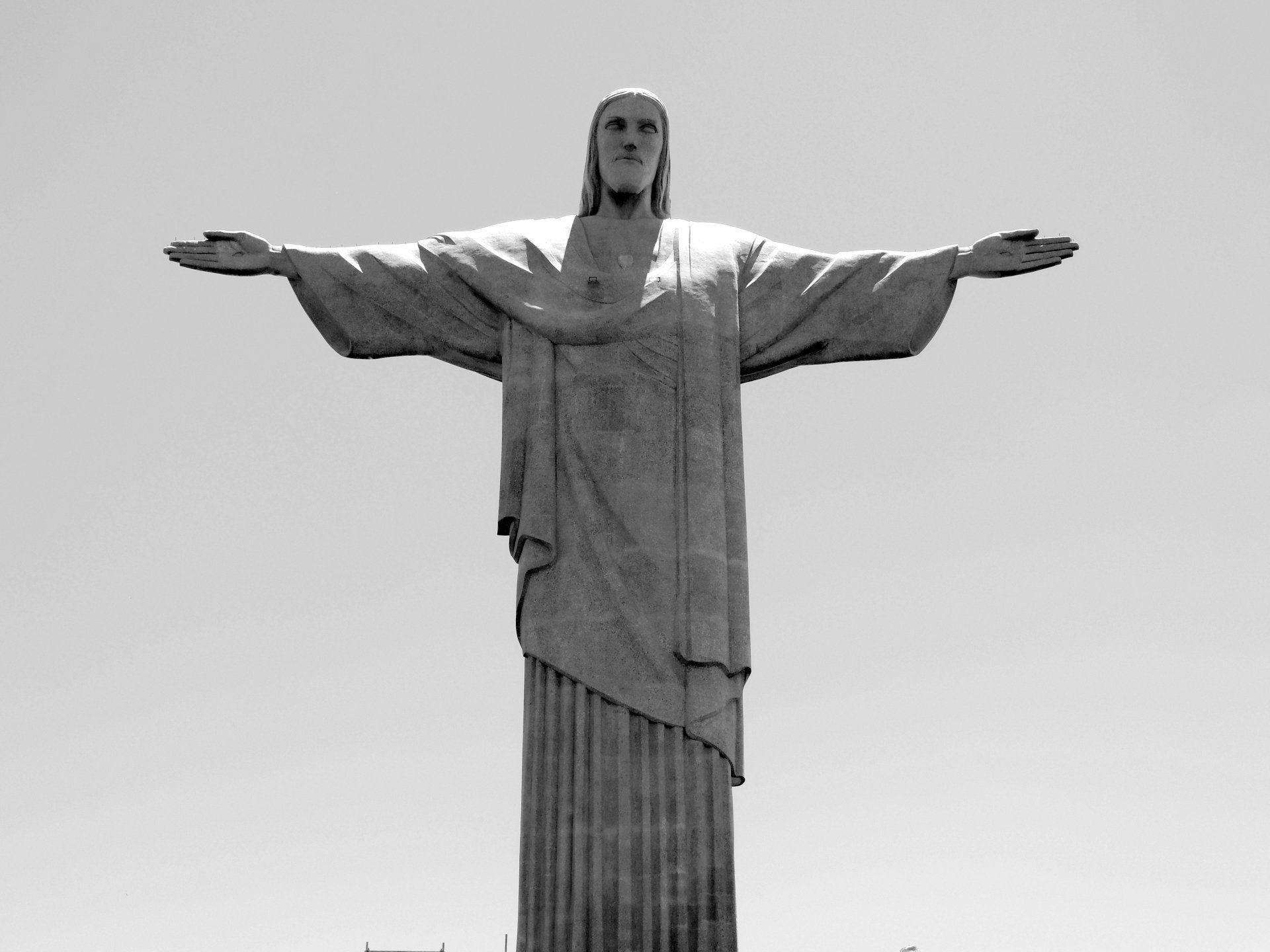 The Christ the Redeemer statue in Rio de Janeiro, Brazil, stands with arms outstretched against a bright sky.