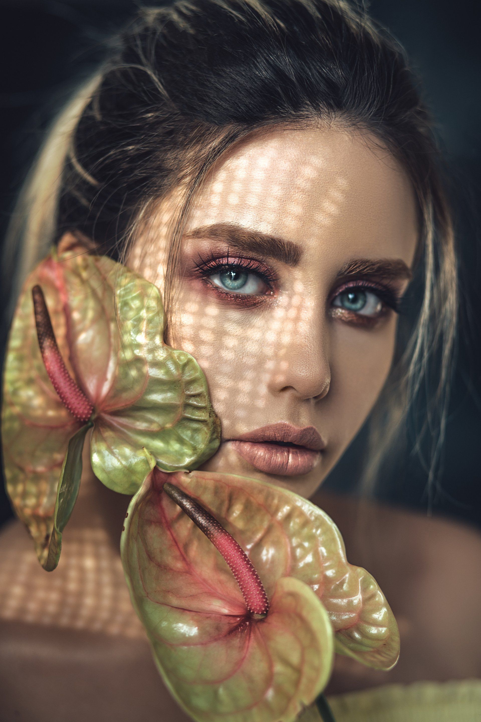 A woman is holding a flower in front of her face.