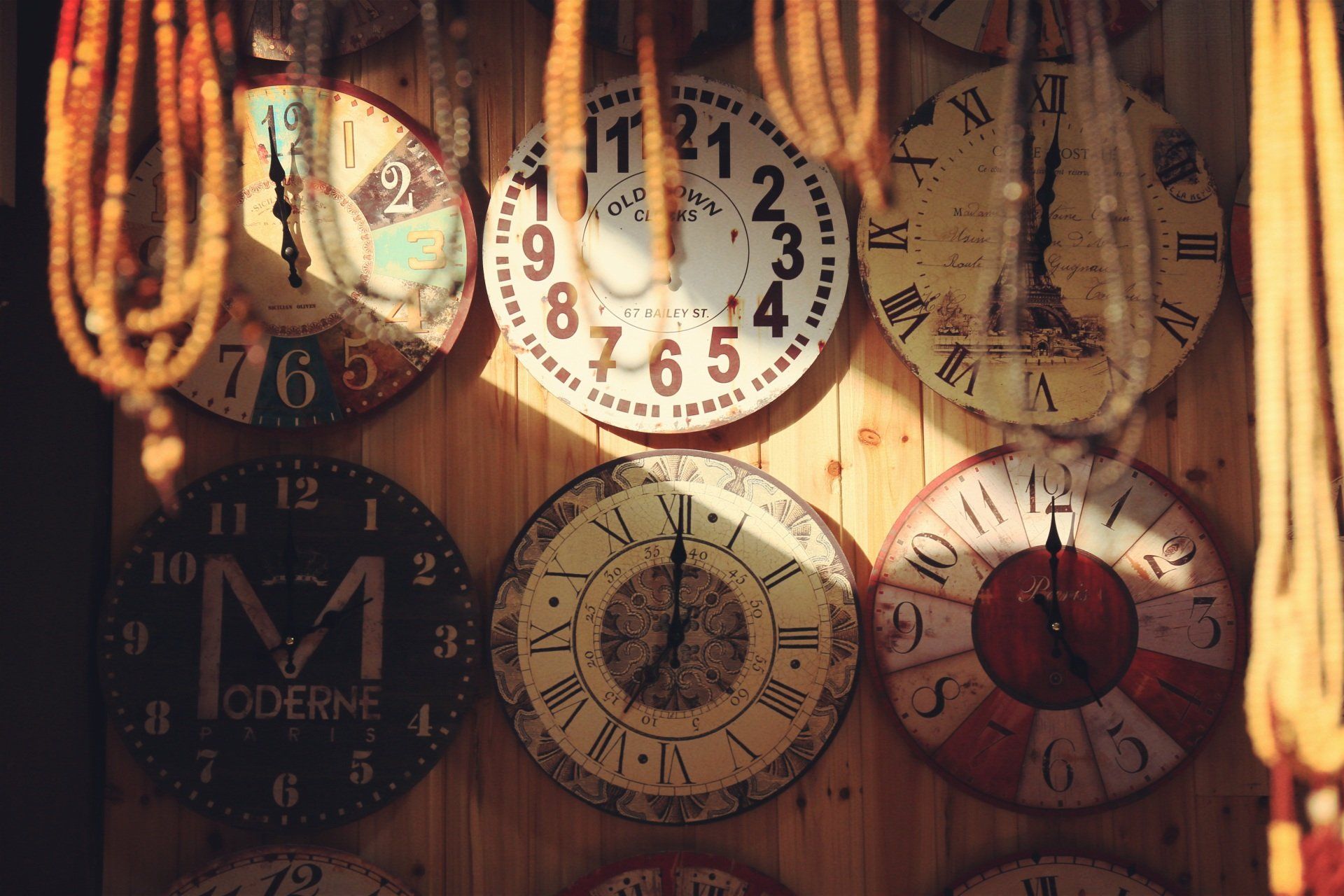 several clocks on a wall beads hanging orange sun