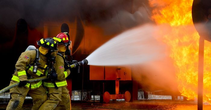 Two firefighters are spraying water on a fire.