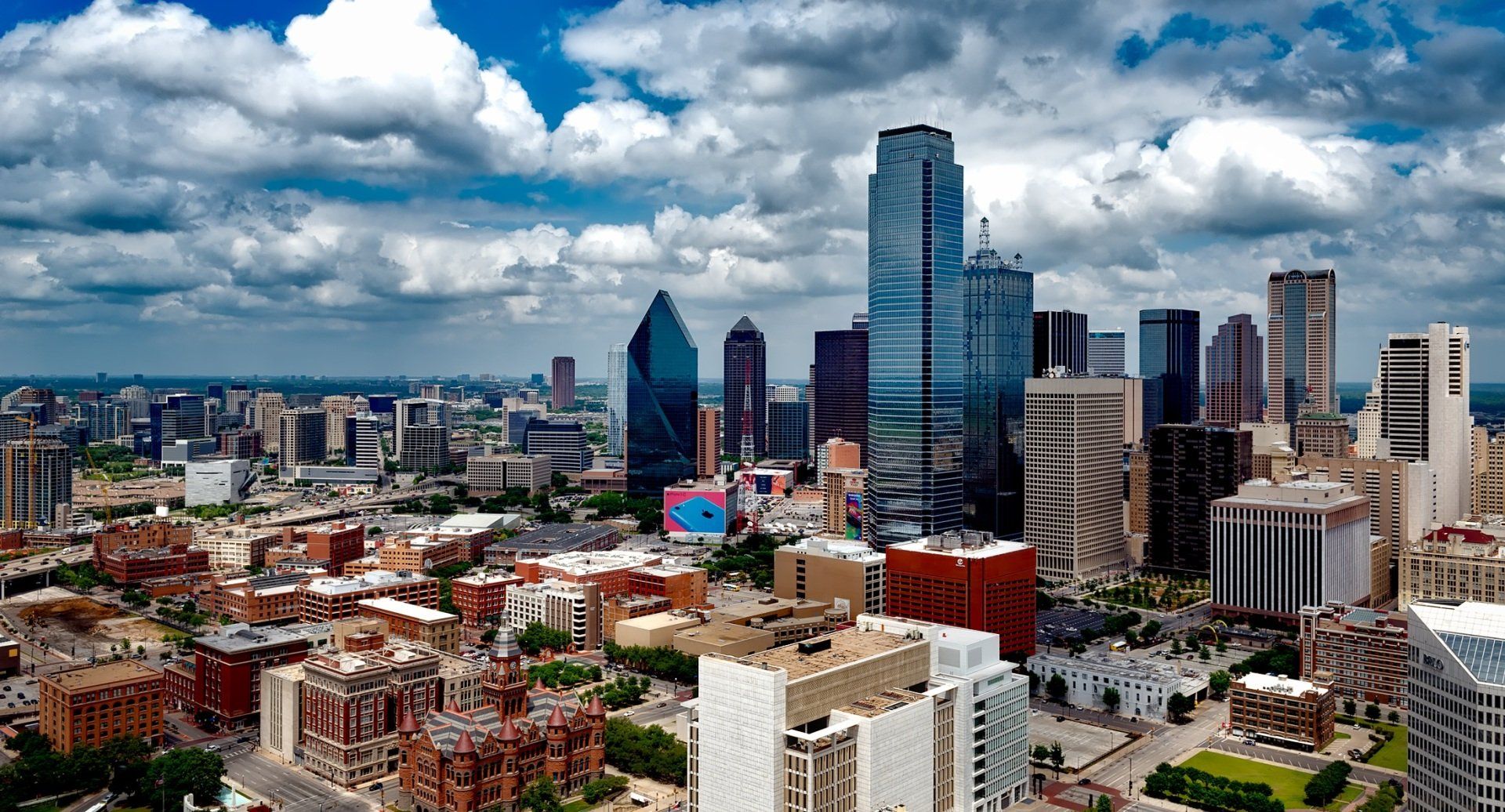 Modern city skyline with tall glass skyscrapers under dramatic cloudy sky