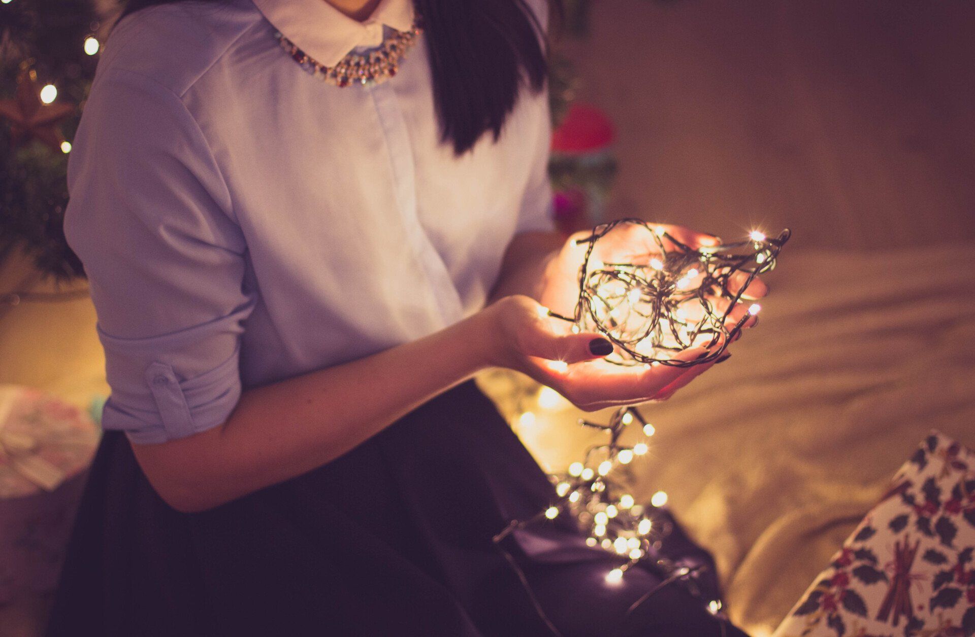 A woman is holding a string of christmas lights in her hands.