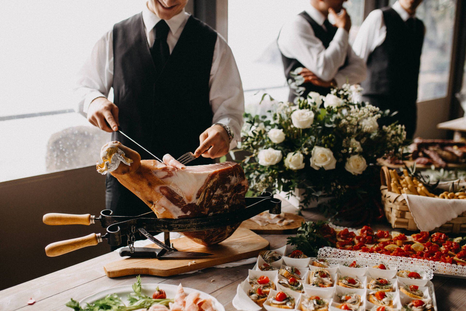 A man is cutting a piece of ham on a cutting board.