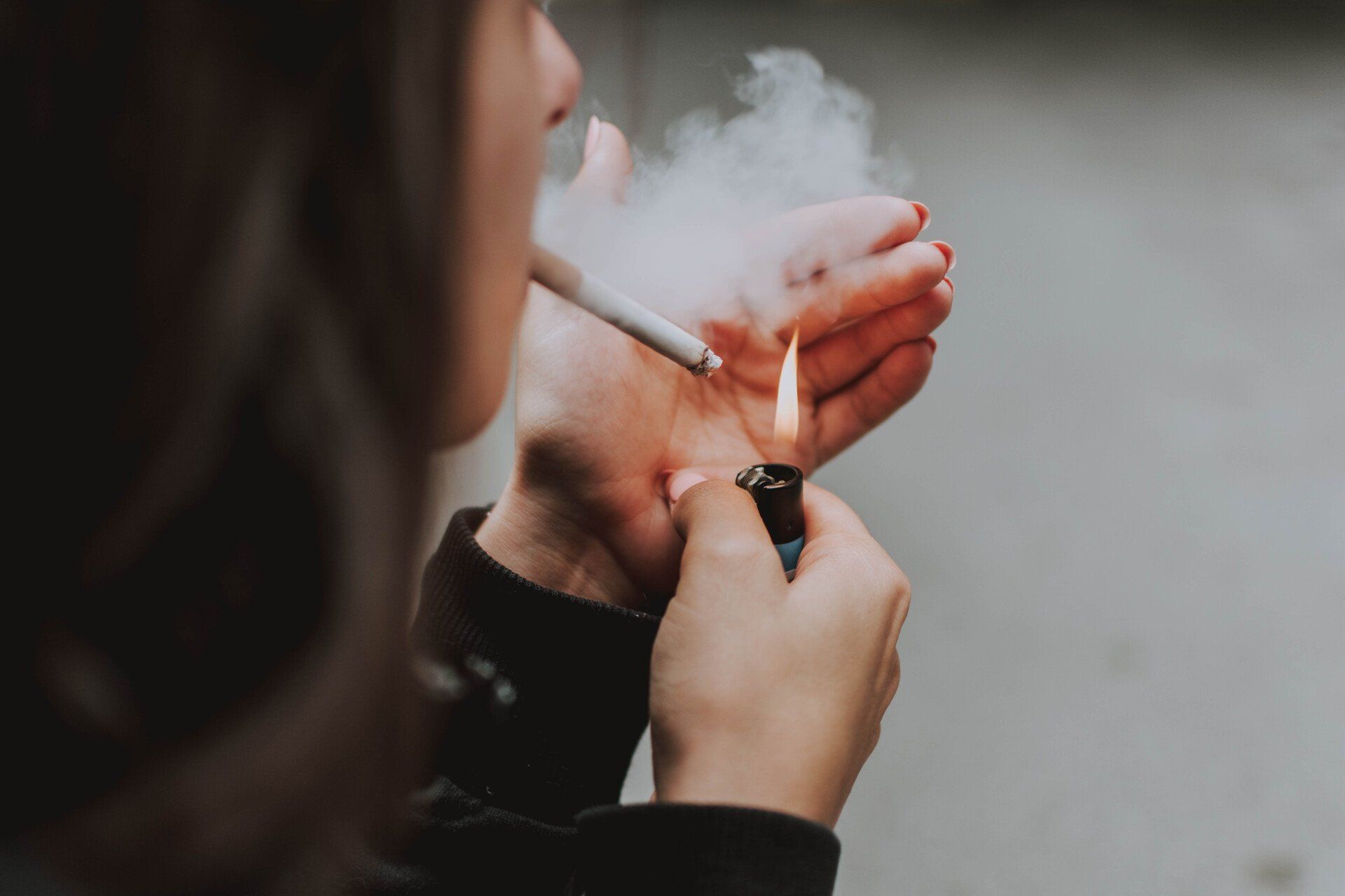 A woman lighting and smoking a cigarette.
