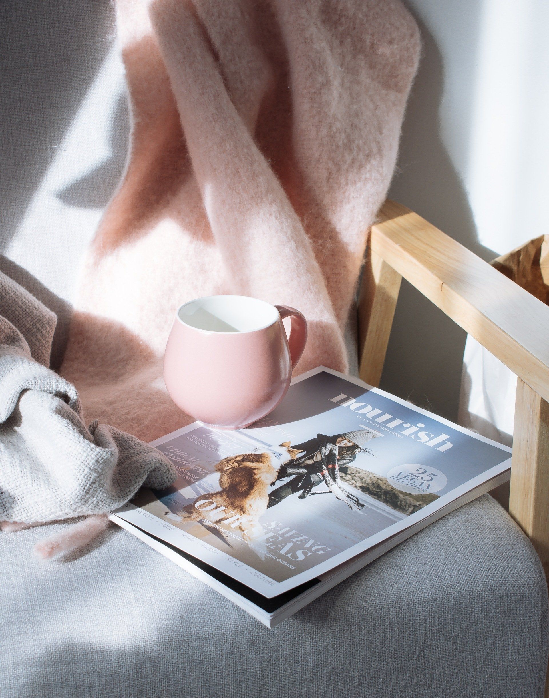 Pink mug on magazine atop a chair with a pink blanket draped over it. Toronto Web Marketing 