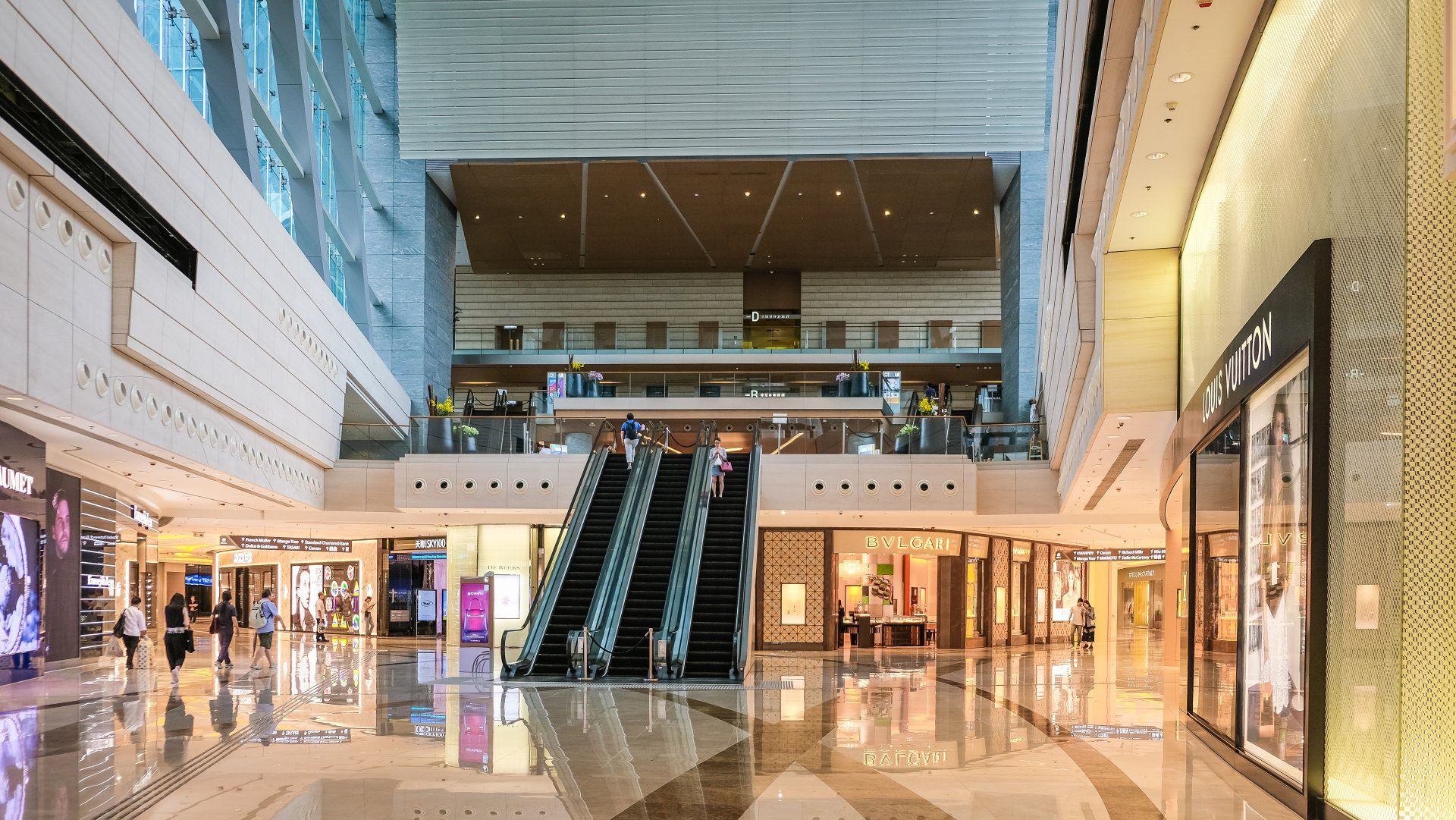 A large empty shopping mall with escalators going up and down.