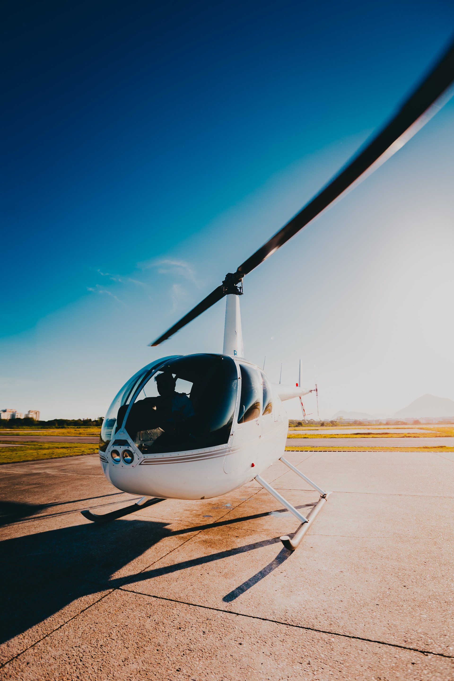 a small white helicopter is parked on a runway .