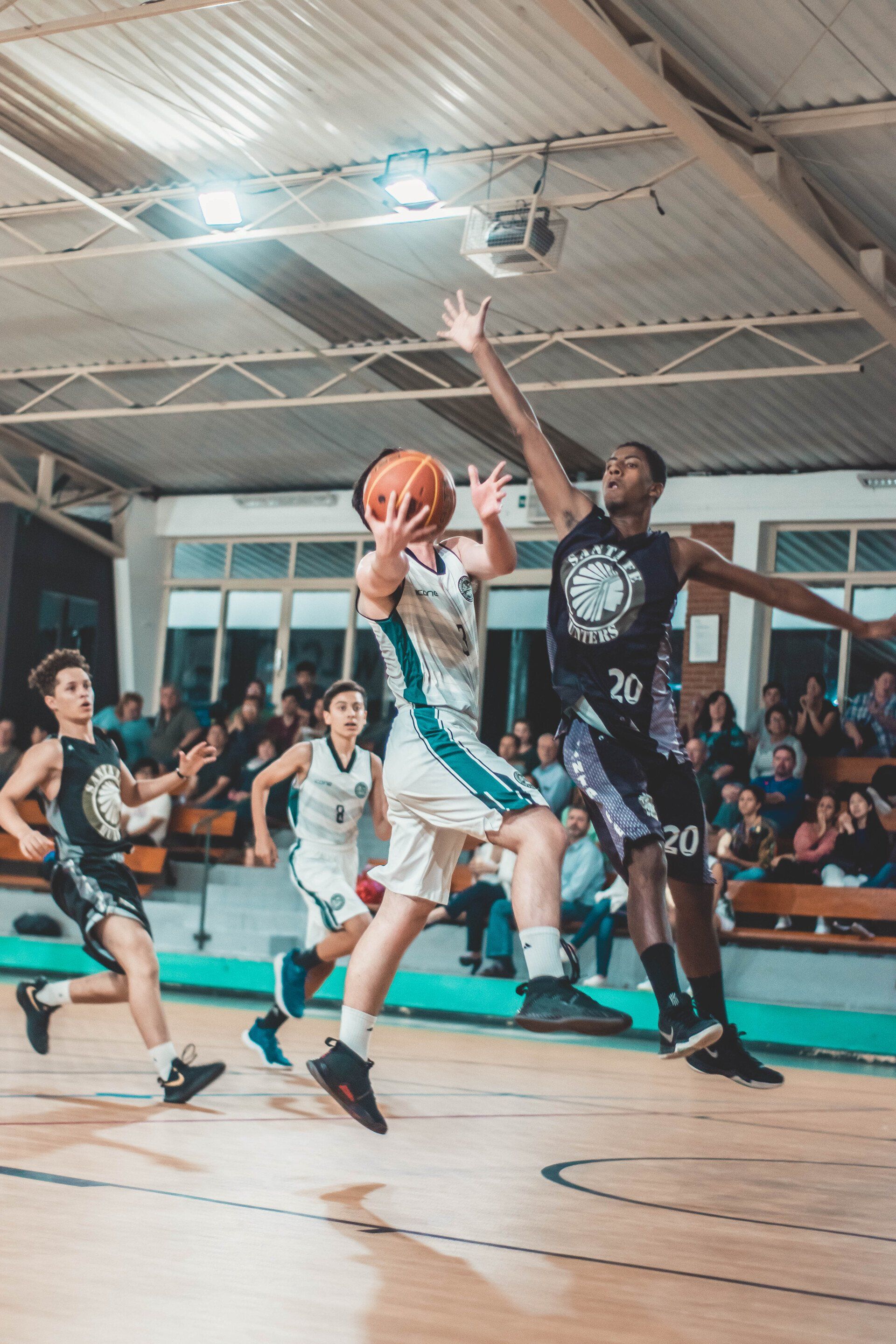 A group of young men are playing basketball on a court.