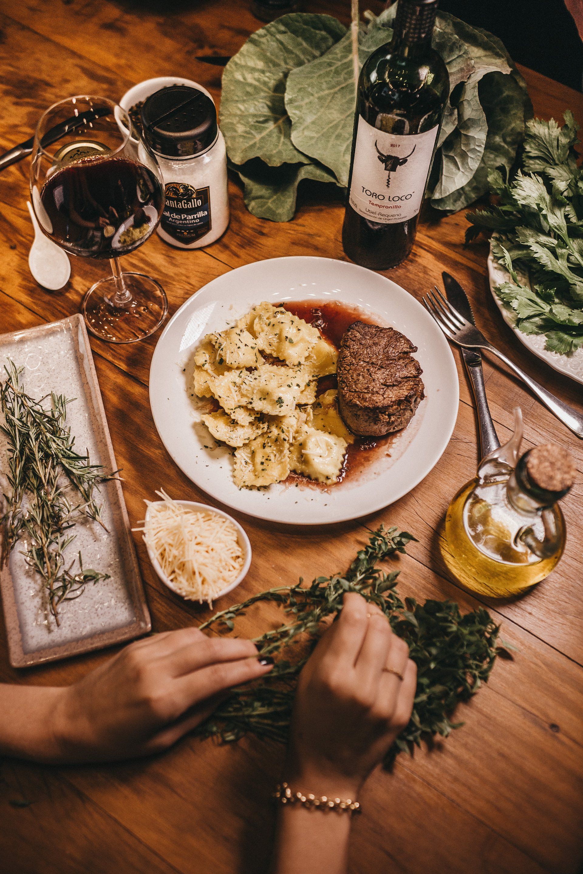 A person is sitting at a table with a plate of food and a bottle of wine.