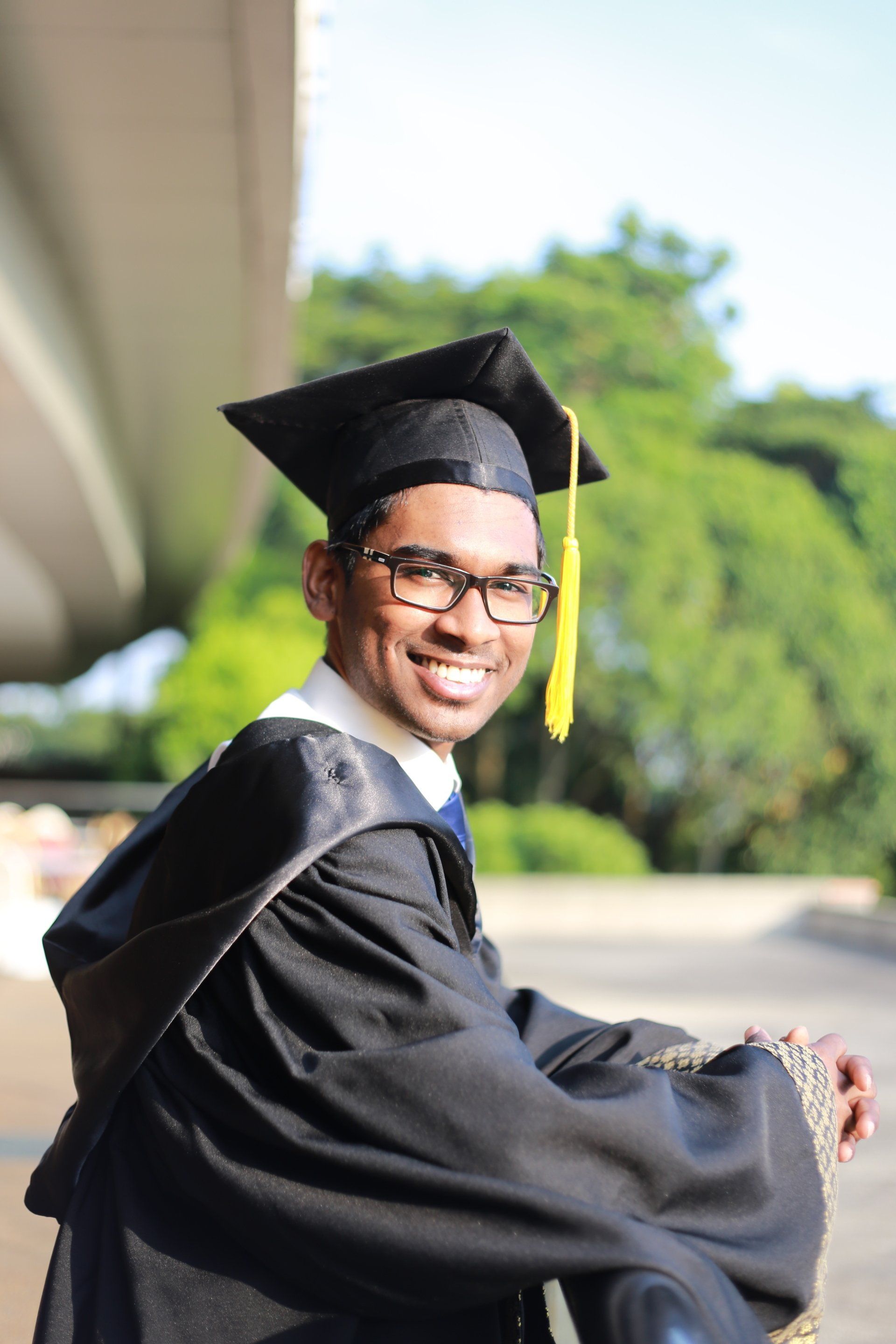 A man in a graduation cap and gown is smiling for the camera.
