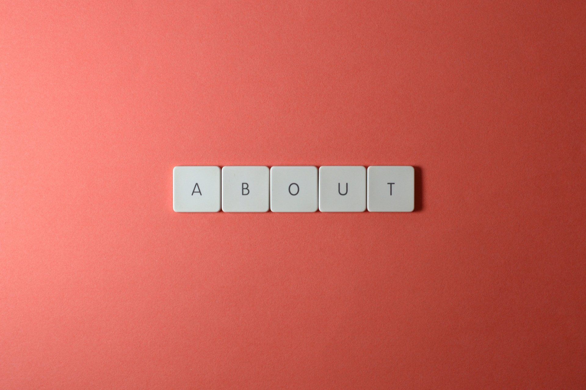 Gray letter tiles spelling “ABOUT” on a red background.