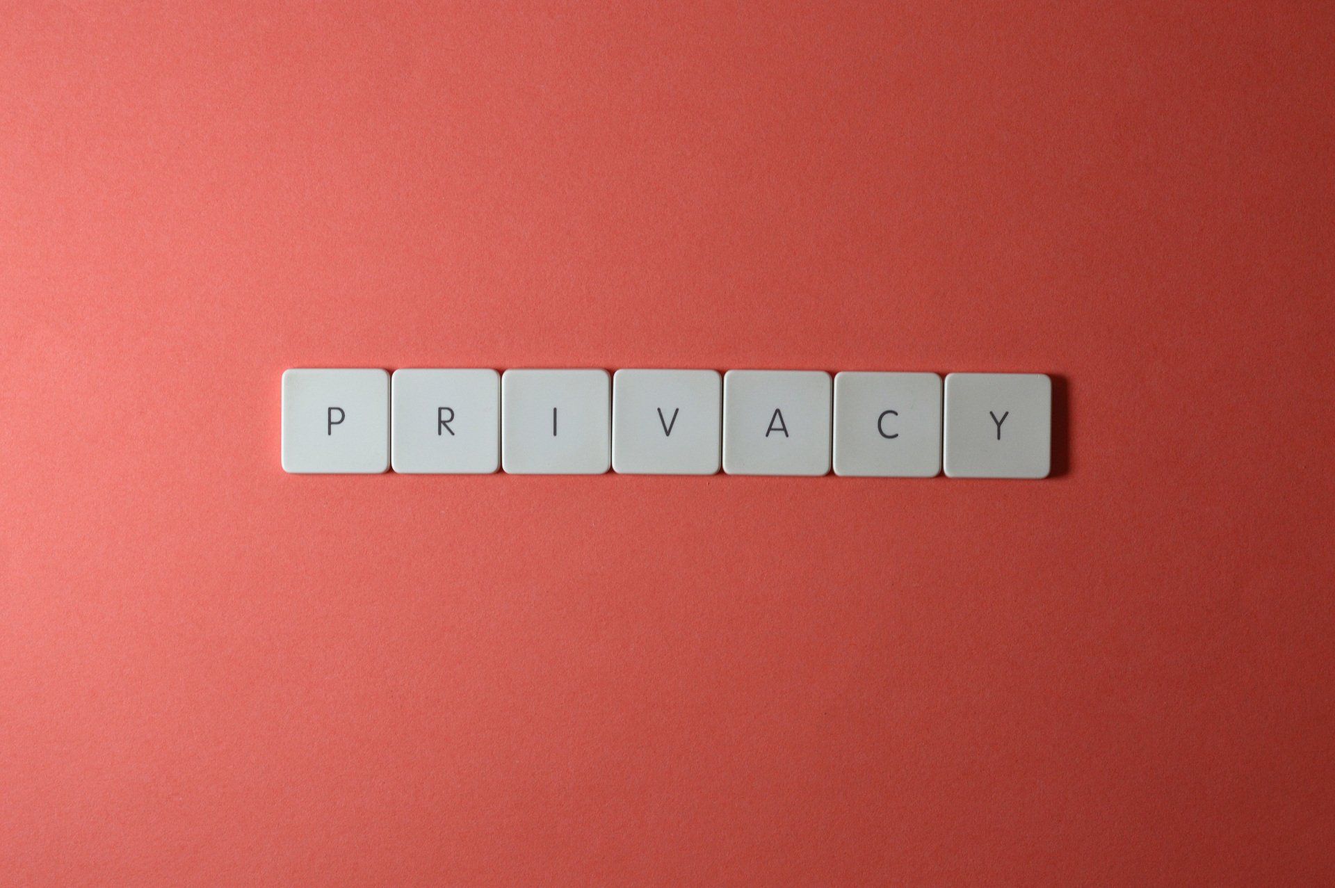 The word privacy is written in scrabble tiles on a red background.