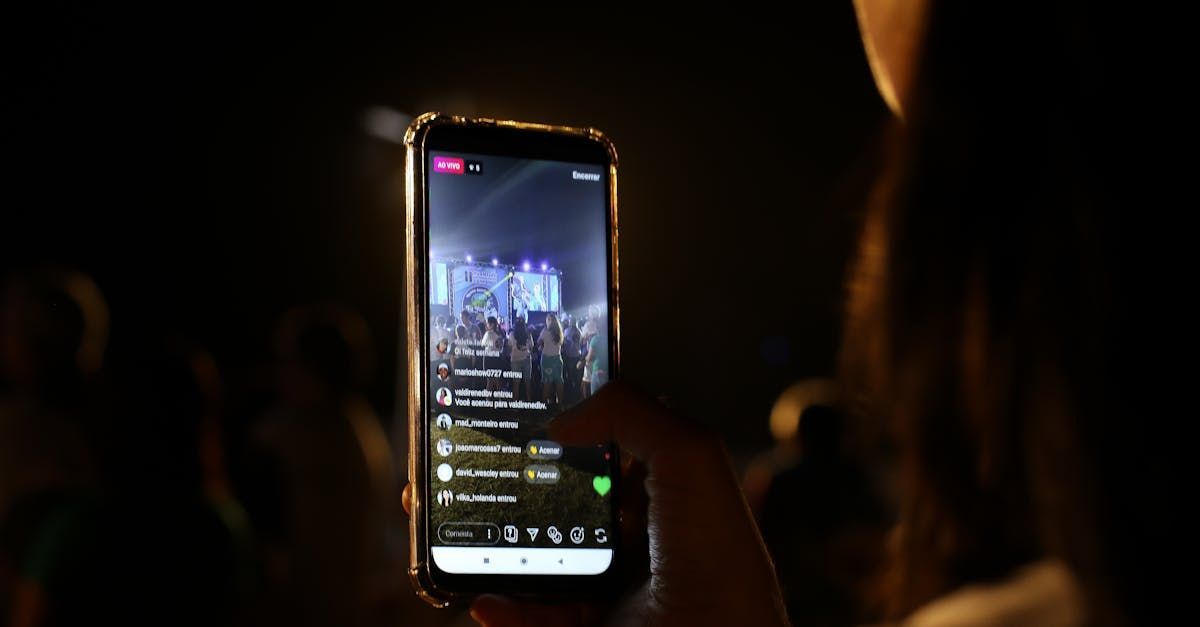 A person is holding a cell phone in their hand and taking a picture of a concert.