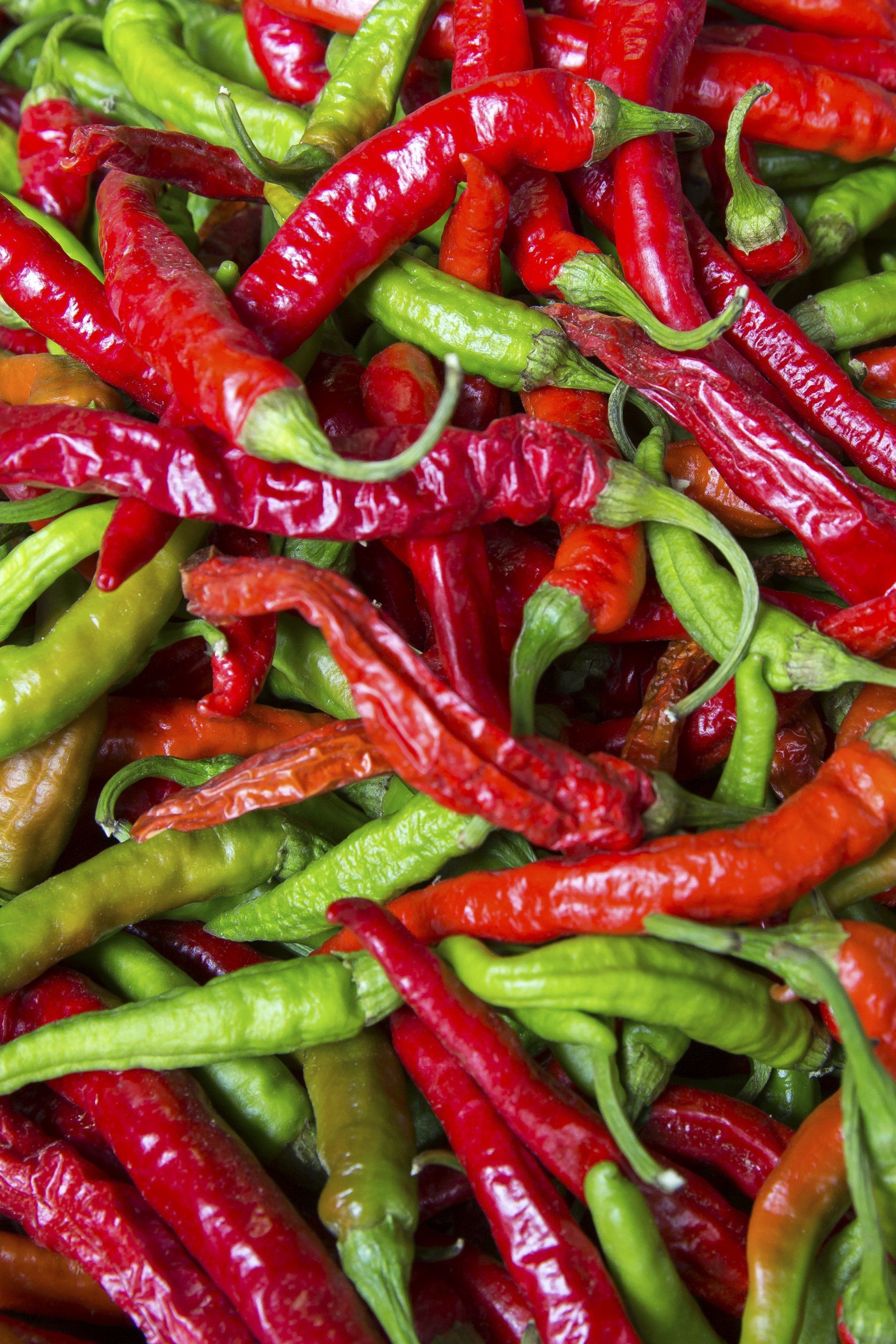 A pile of red and green peppers are stacked on top of each other.