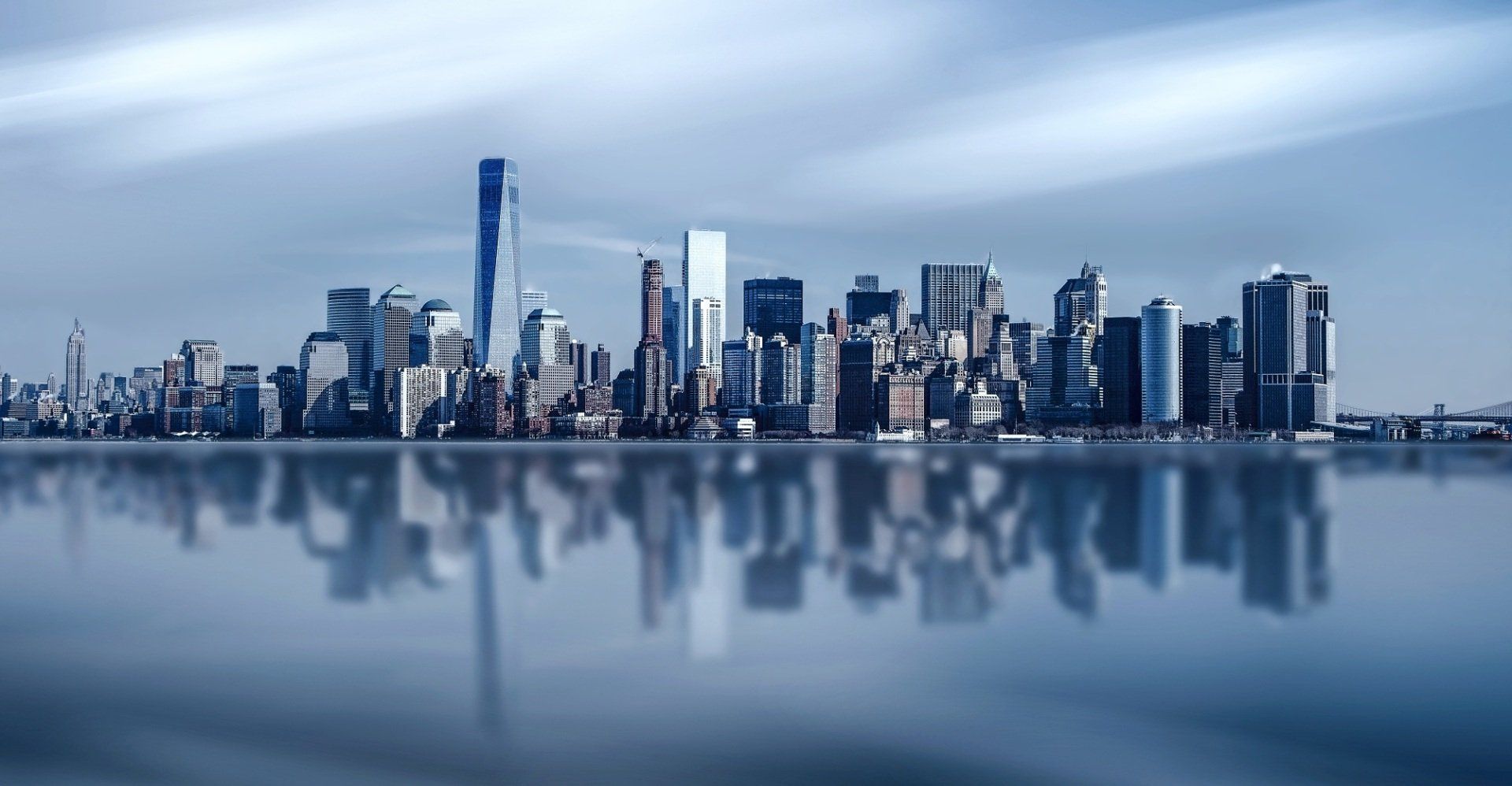 Die Skyline der Stadt spiegelt sich im ruhigen Wasser. Gebäude in Blautönen.