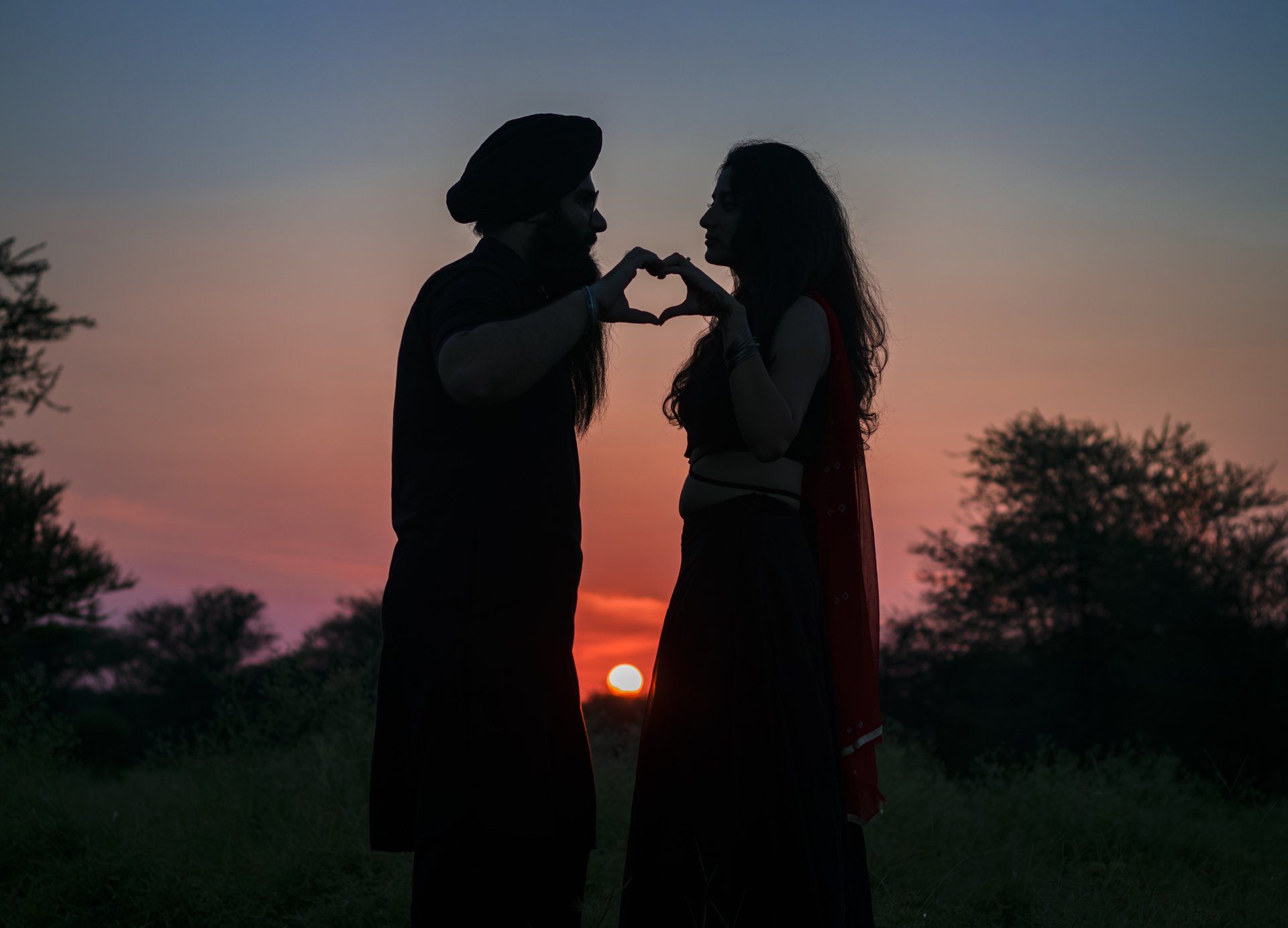 shadows of couple at sunset heart hands