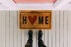 somebody standing on a porch in front of a welcome mat that says "home"