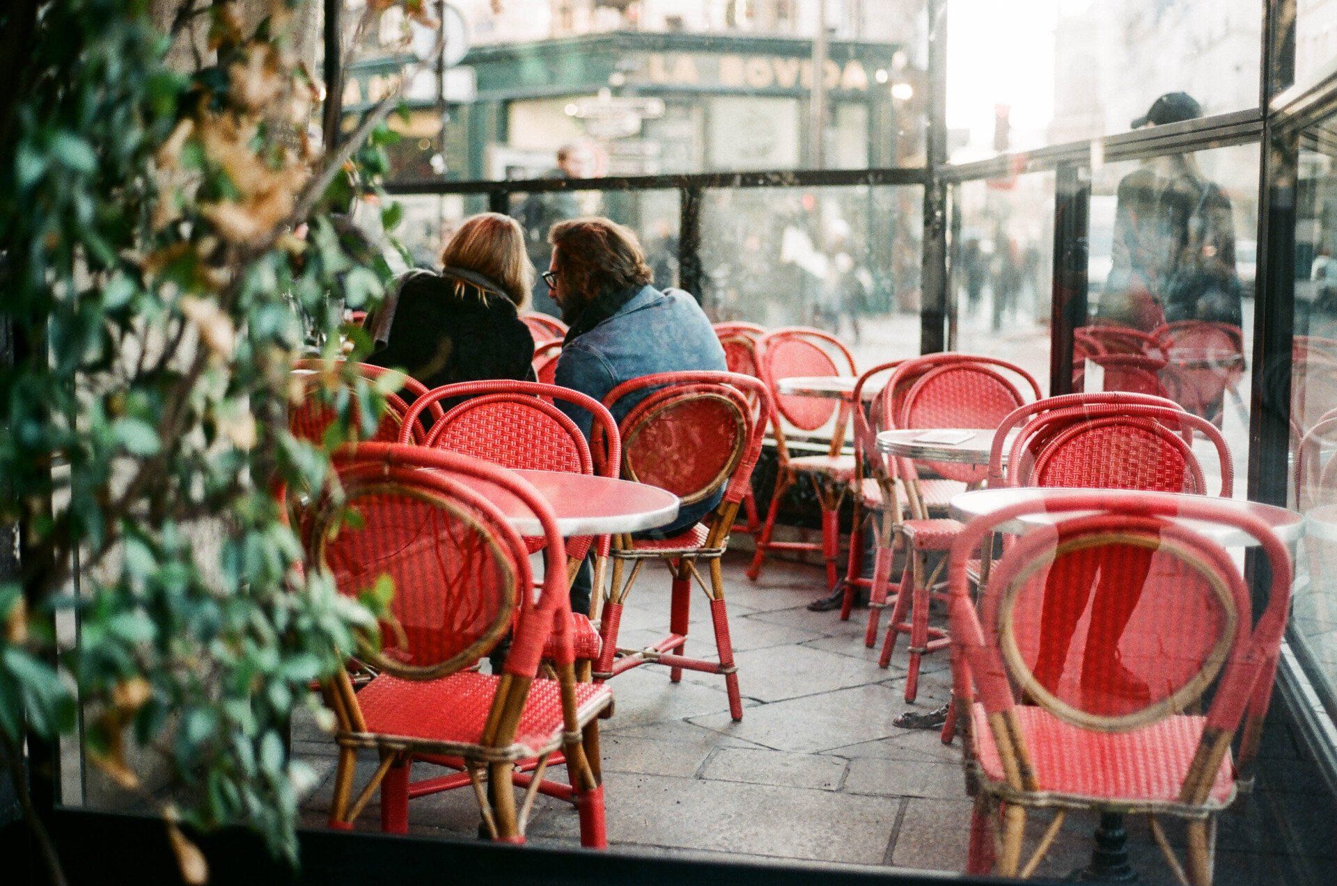 Front restaurant technology about us couple sitting in restaurant patio area on red wicker chairs