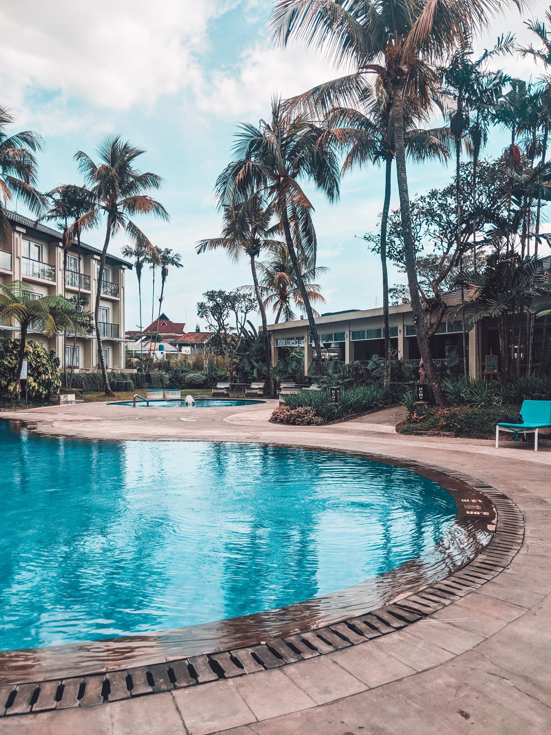 A large swimming pool surrounded by palm trees and buildings