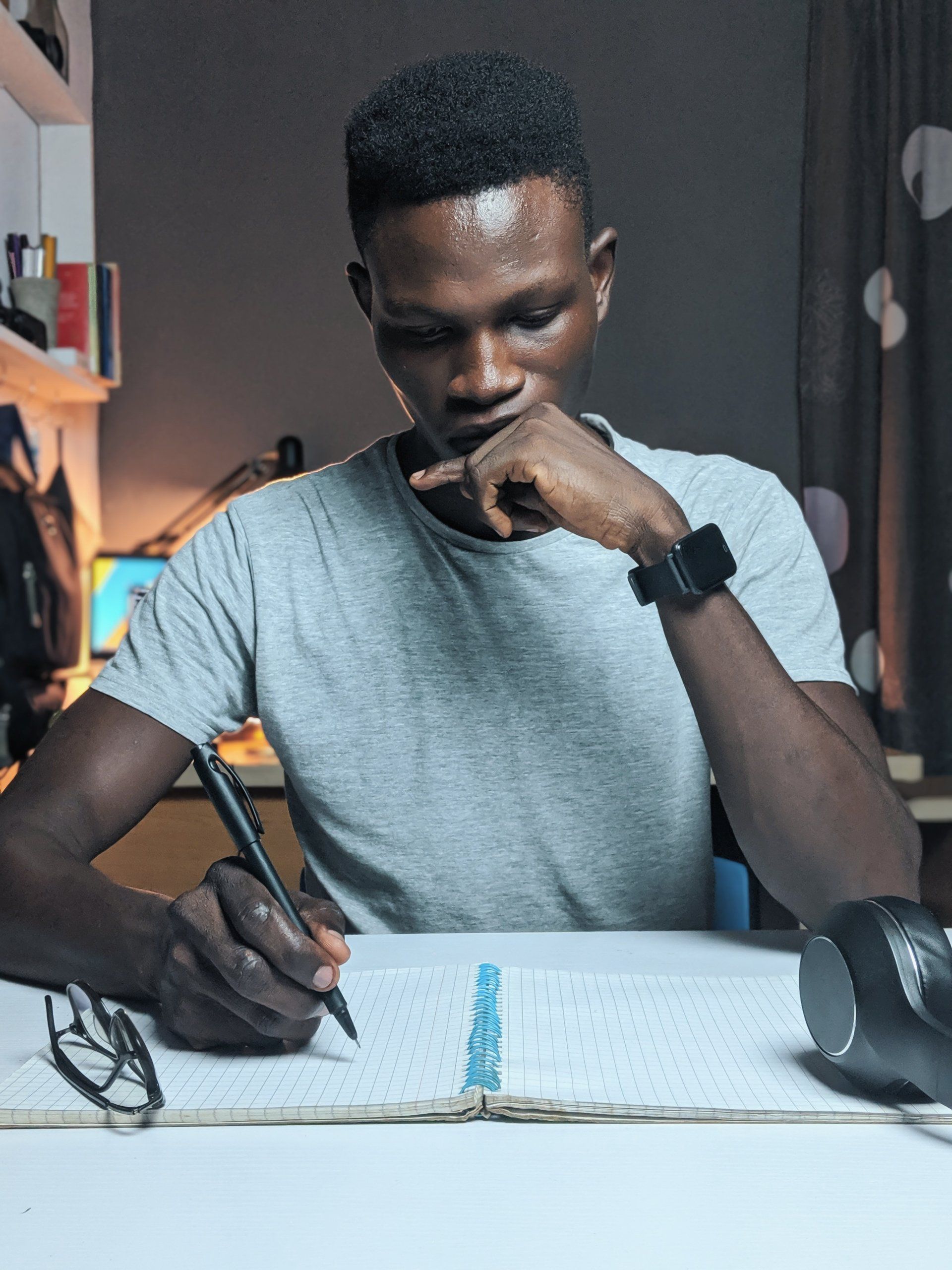 A man is sitting at a desk writing in a notebook.