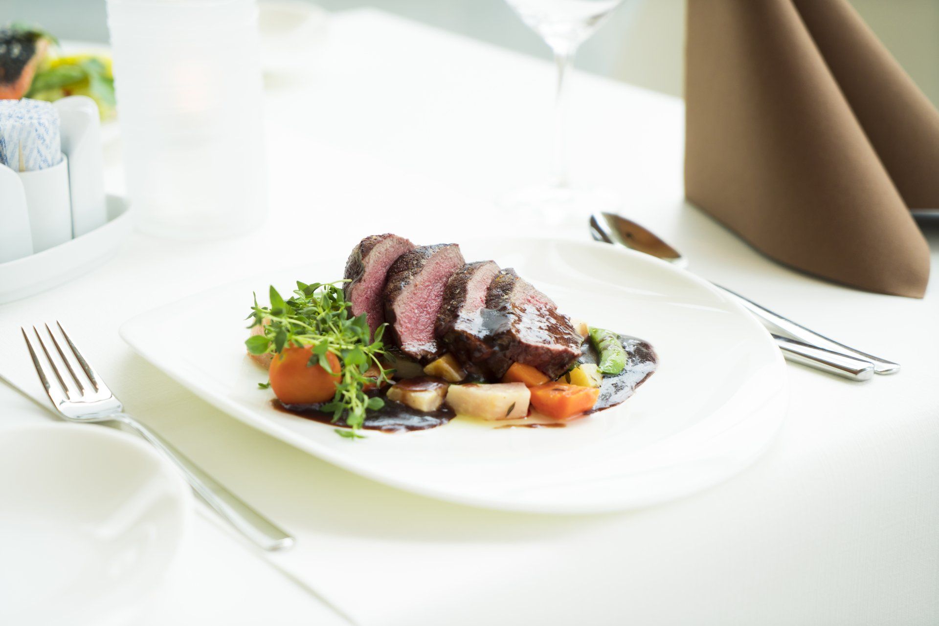 A white plate topped with meat and vegetables on a table.