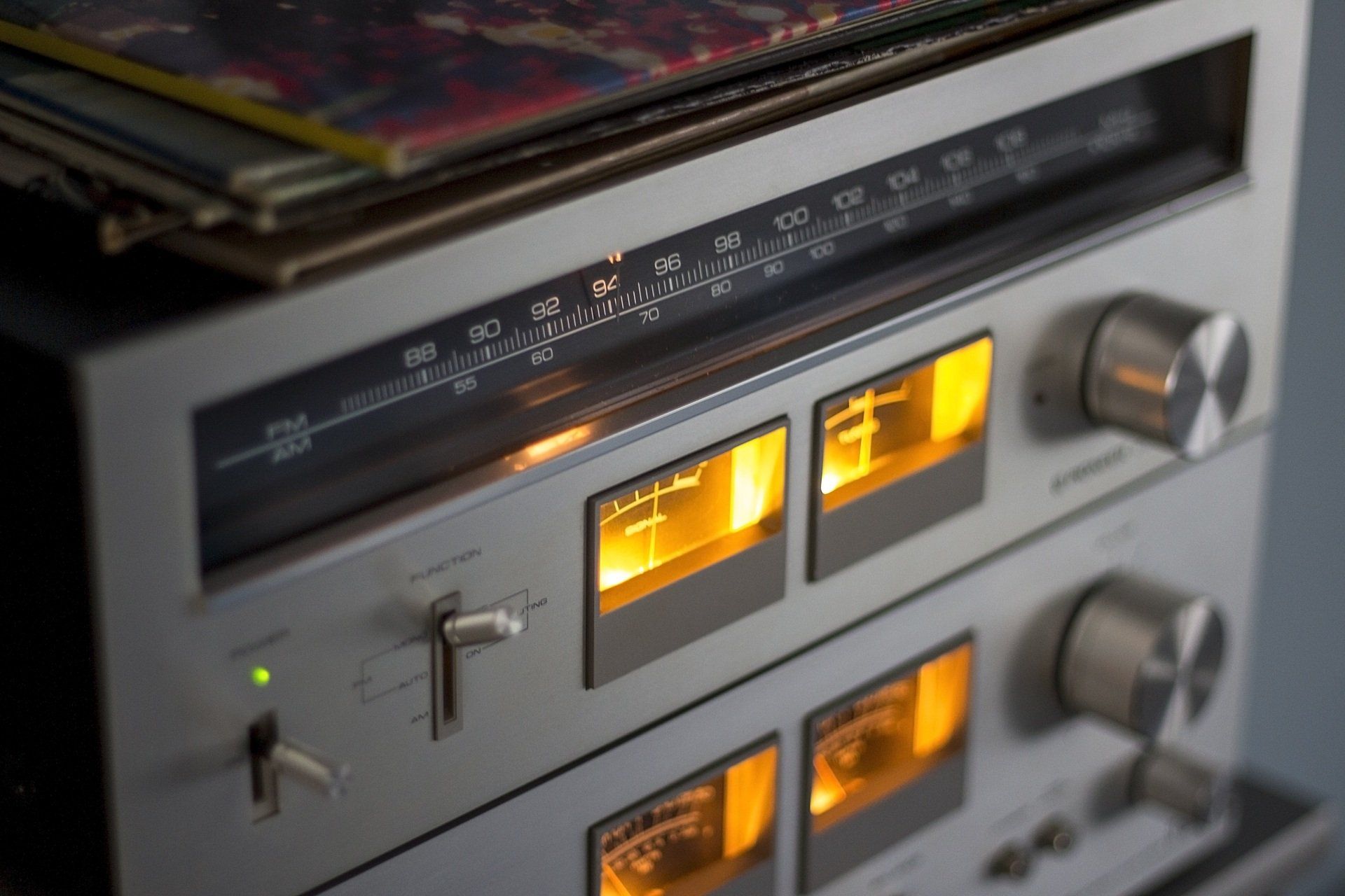 Close-up of a vintage stereo receiver with glowing orange display and silver knobs