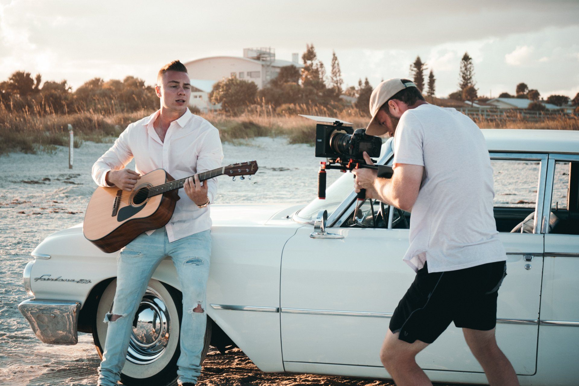 A man is playing a guitar while another man is taking a picture of him.