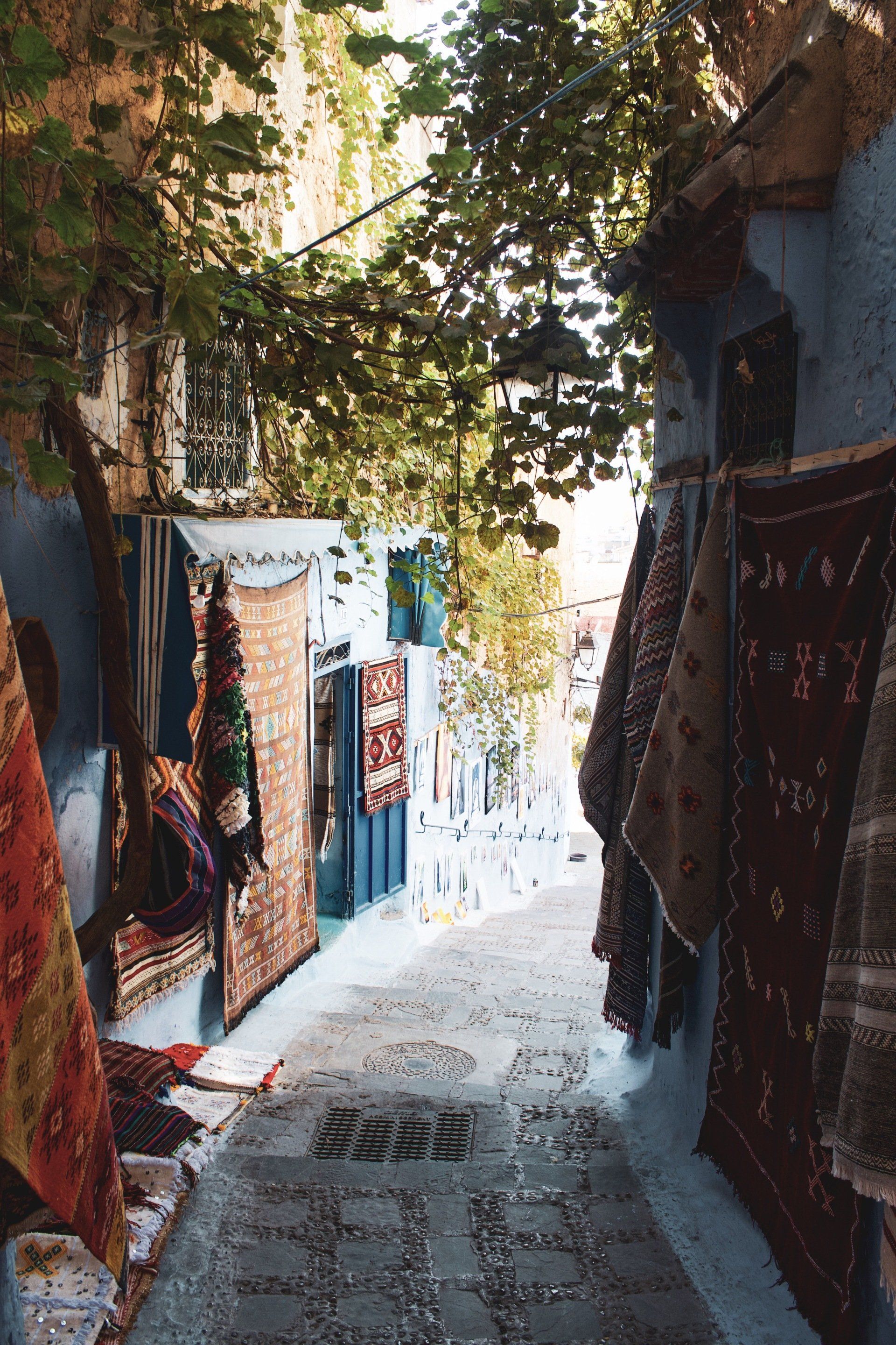 A narrow alleyway with a lot of rugs hanging on the wall.