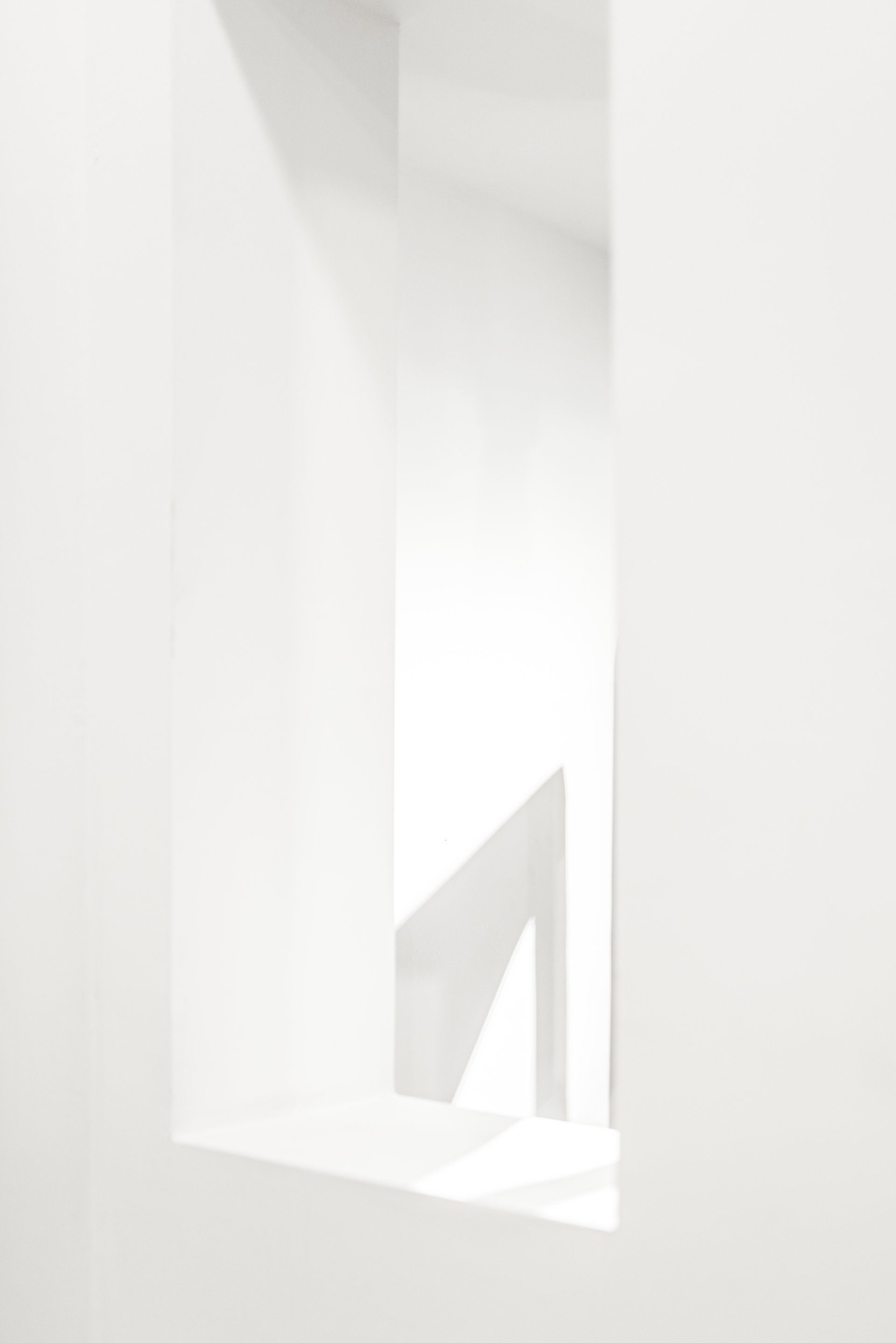 A white wall with a window in it and a staircase in the background.