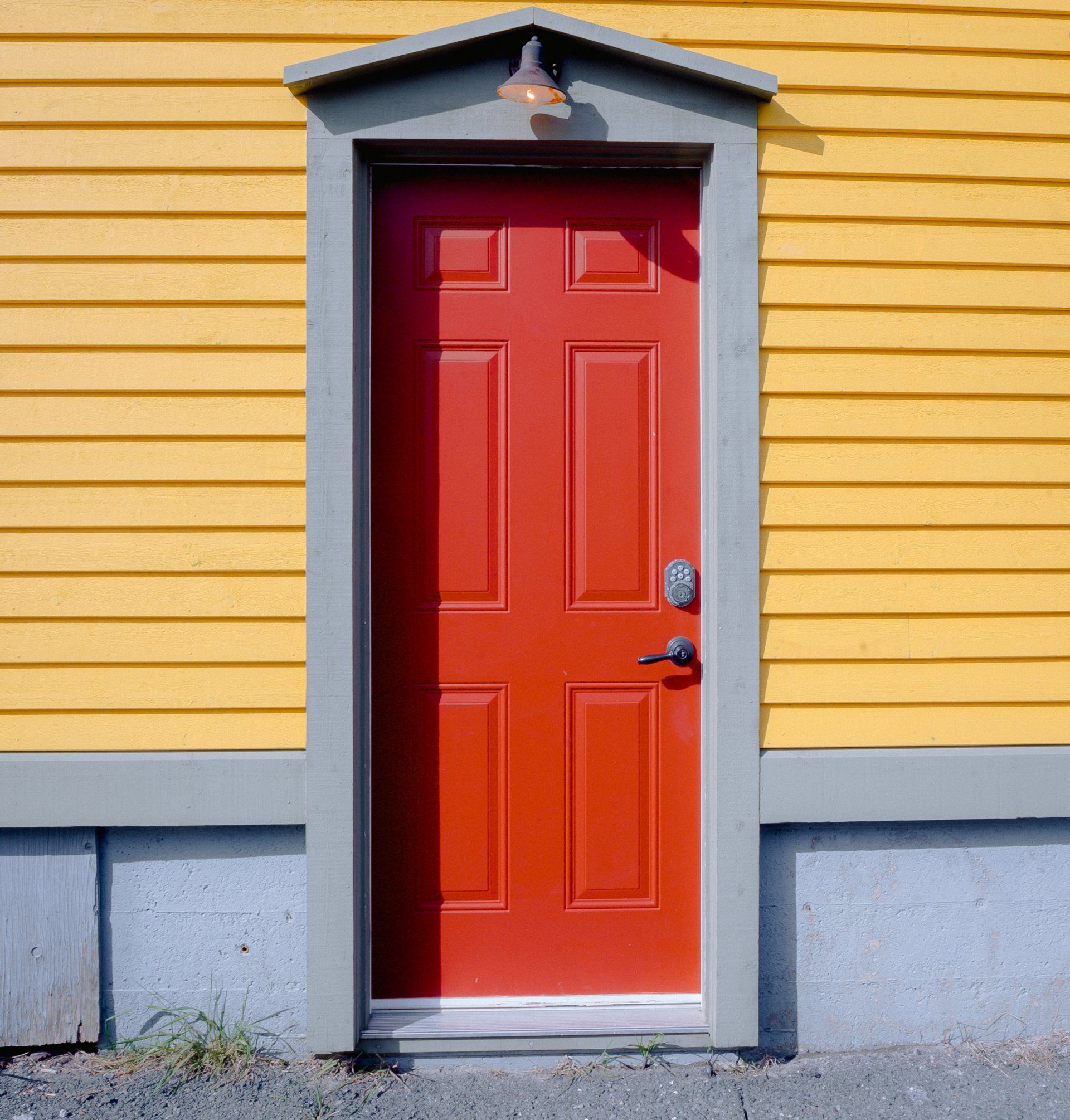 A red door is on a yellow house