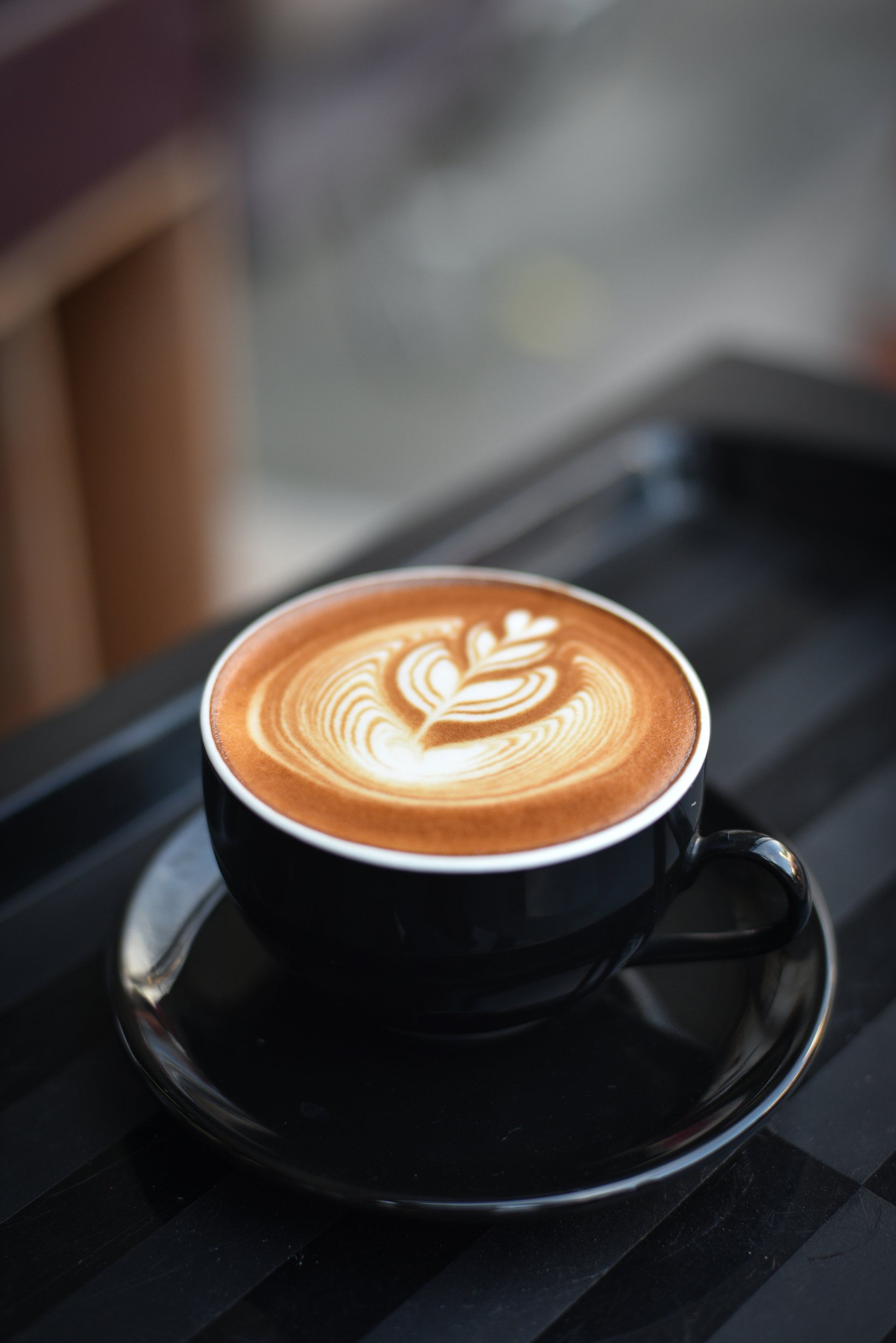 A cup of cappuccino on a saucer on a table.