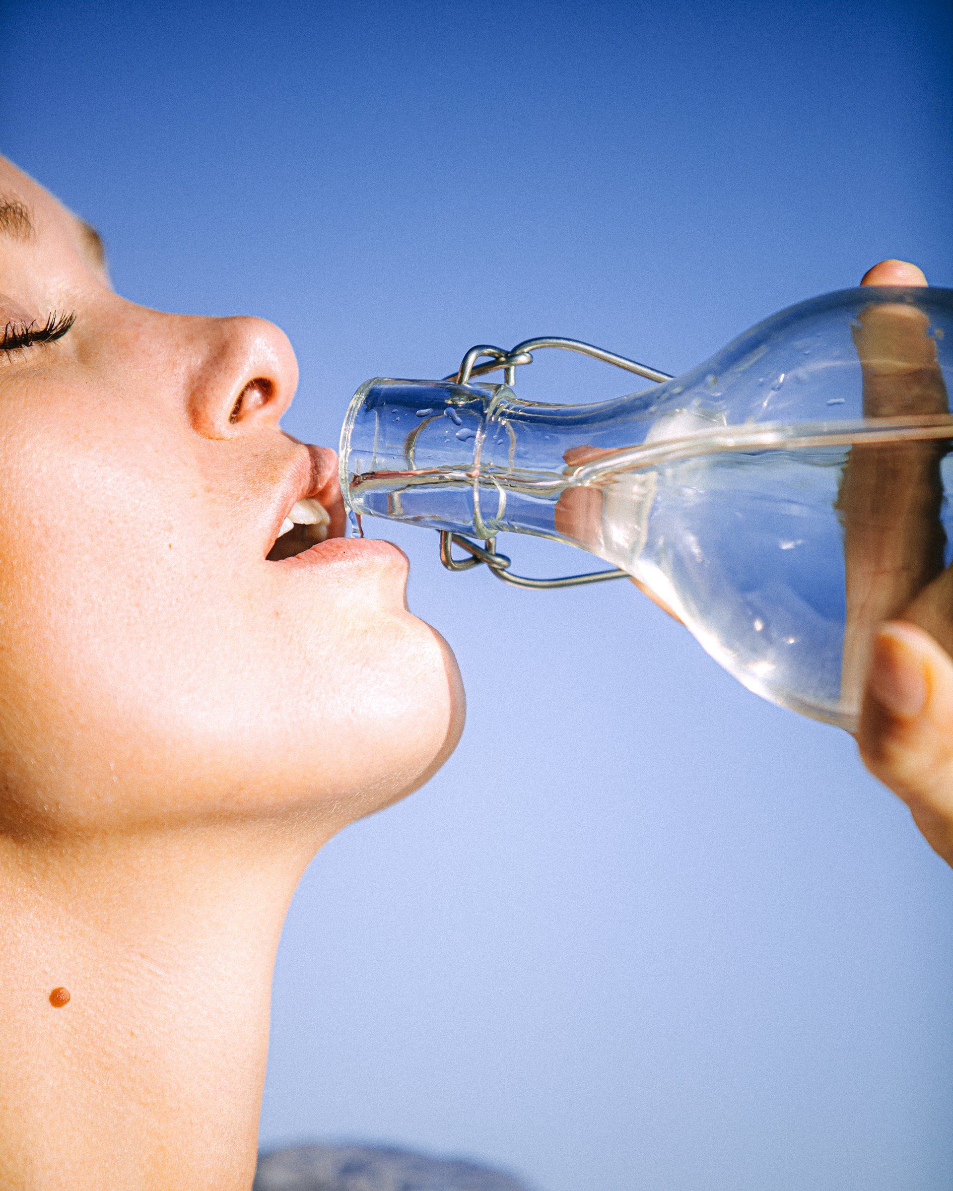 Woman drinking water from glass bottle