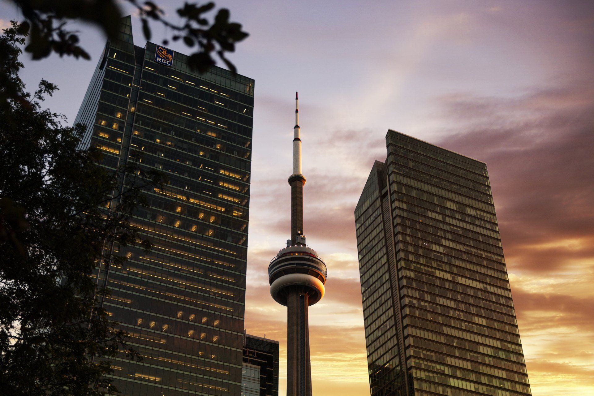 CN Tower and Toronto skyline at sunset with orange and purple hues.