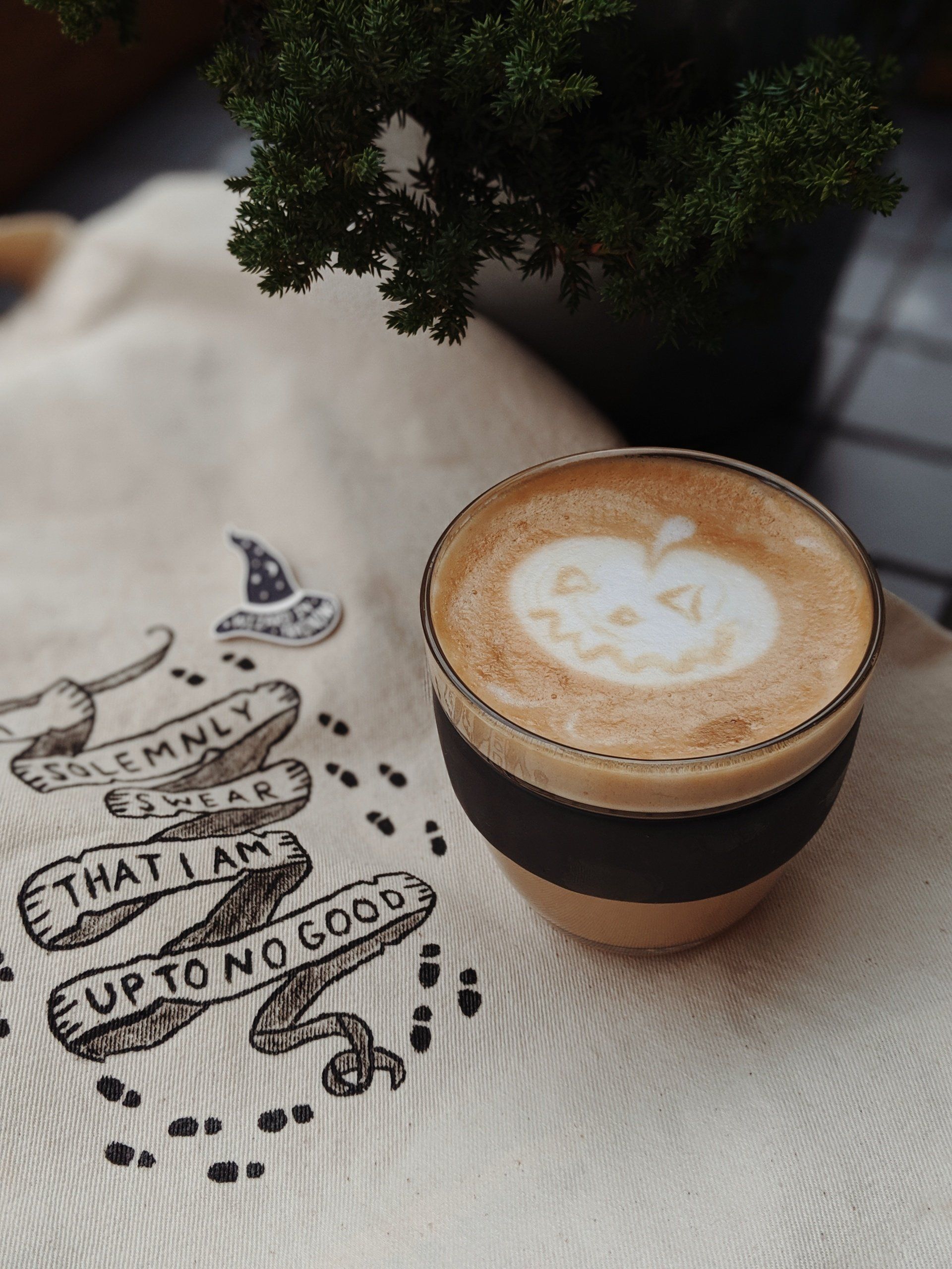 A cup of coffee on a table next to a bag that says that i am cup to no good