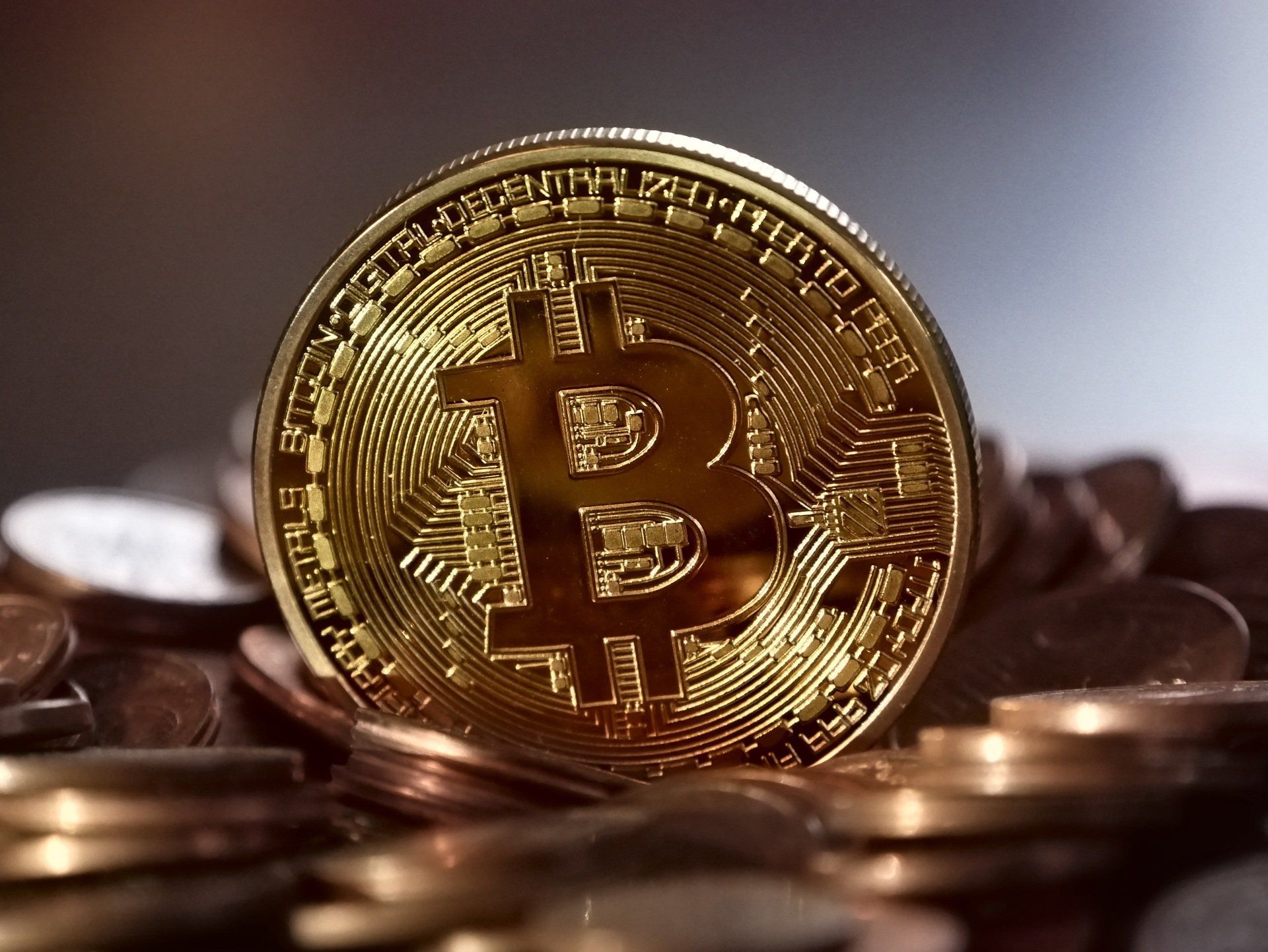 Een gouden Bitcoin-munt bovenop een stapel andere munten.
