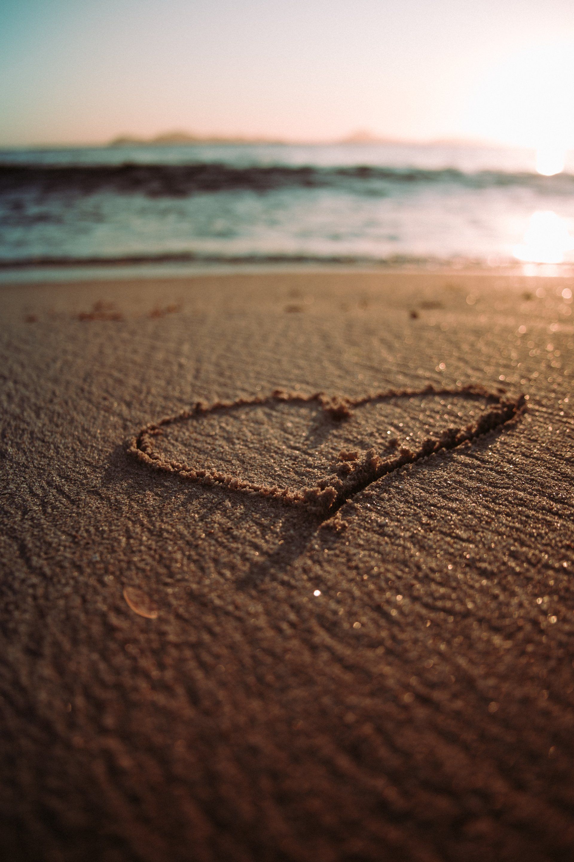 A heart is drawn in the sand on the beach.