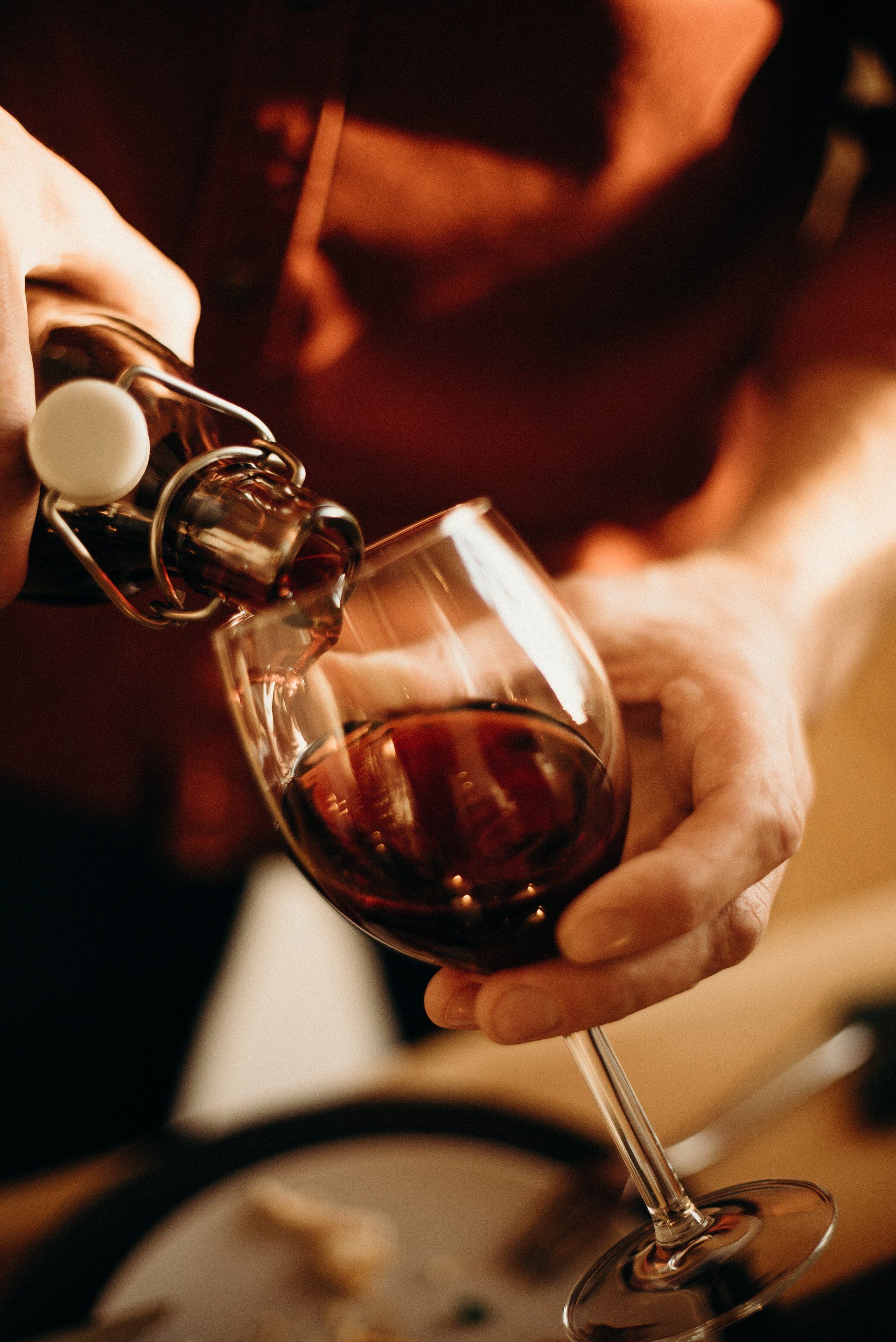 A person pouring a mead from a bottle into a wine glass.