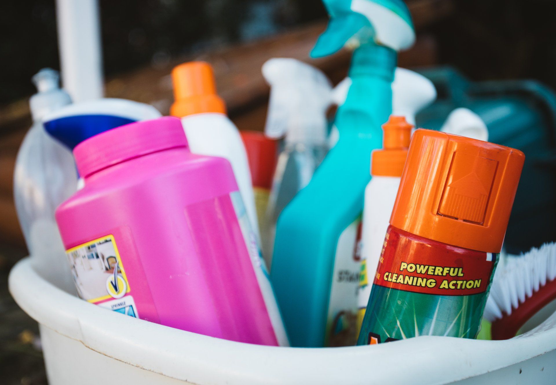 A bucket full of cleaning supplies including a spray bottle that says powerful growing action