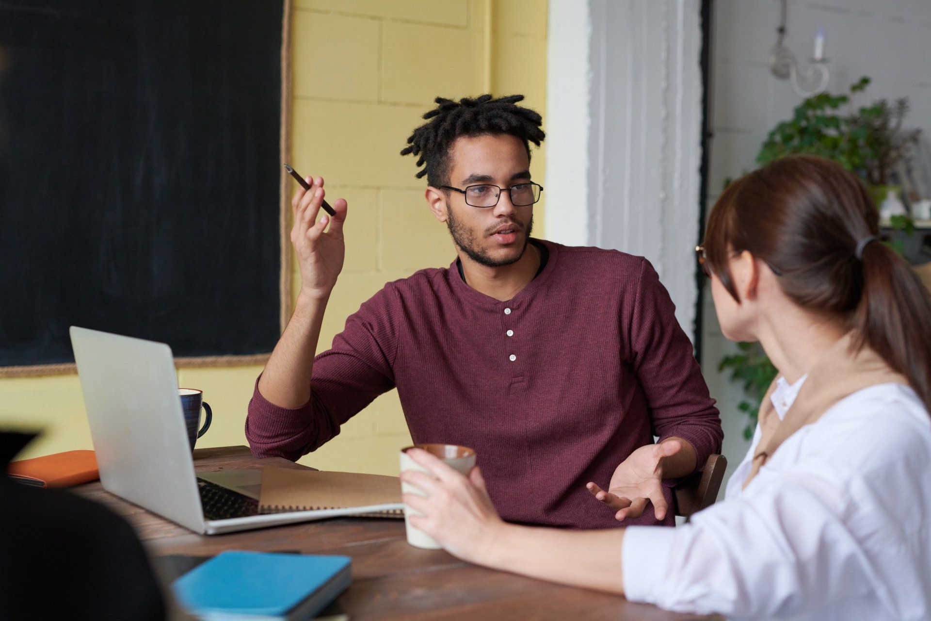 A man and a woman are sitting at a table with a laptop.