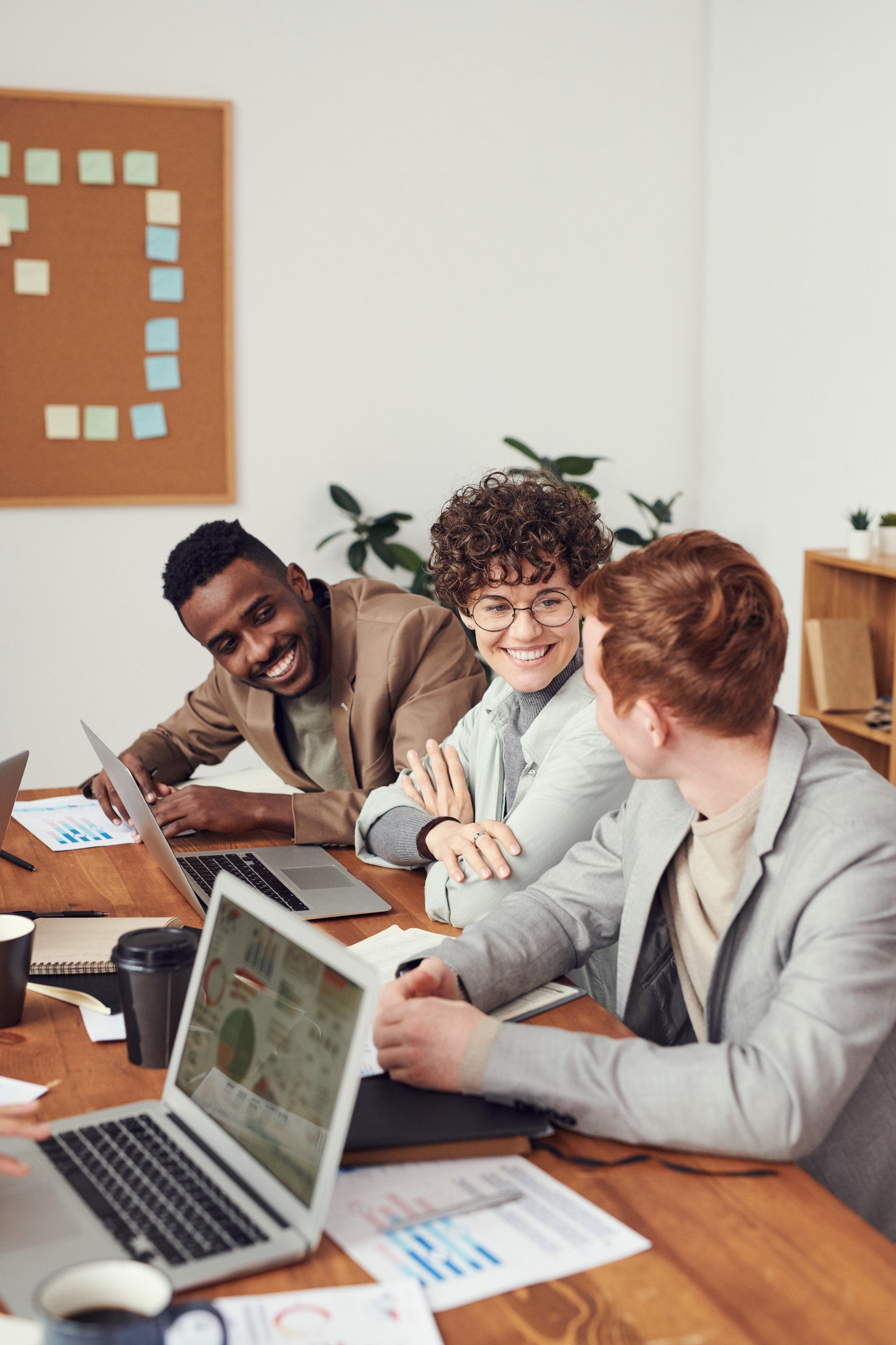 A group of people are sitting at a table with laptops.