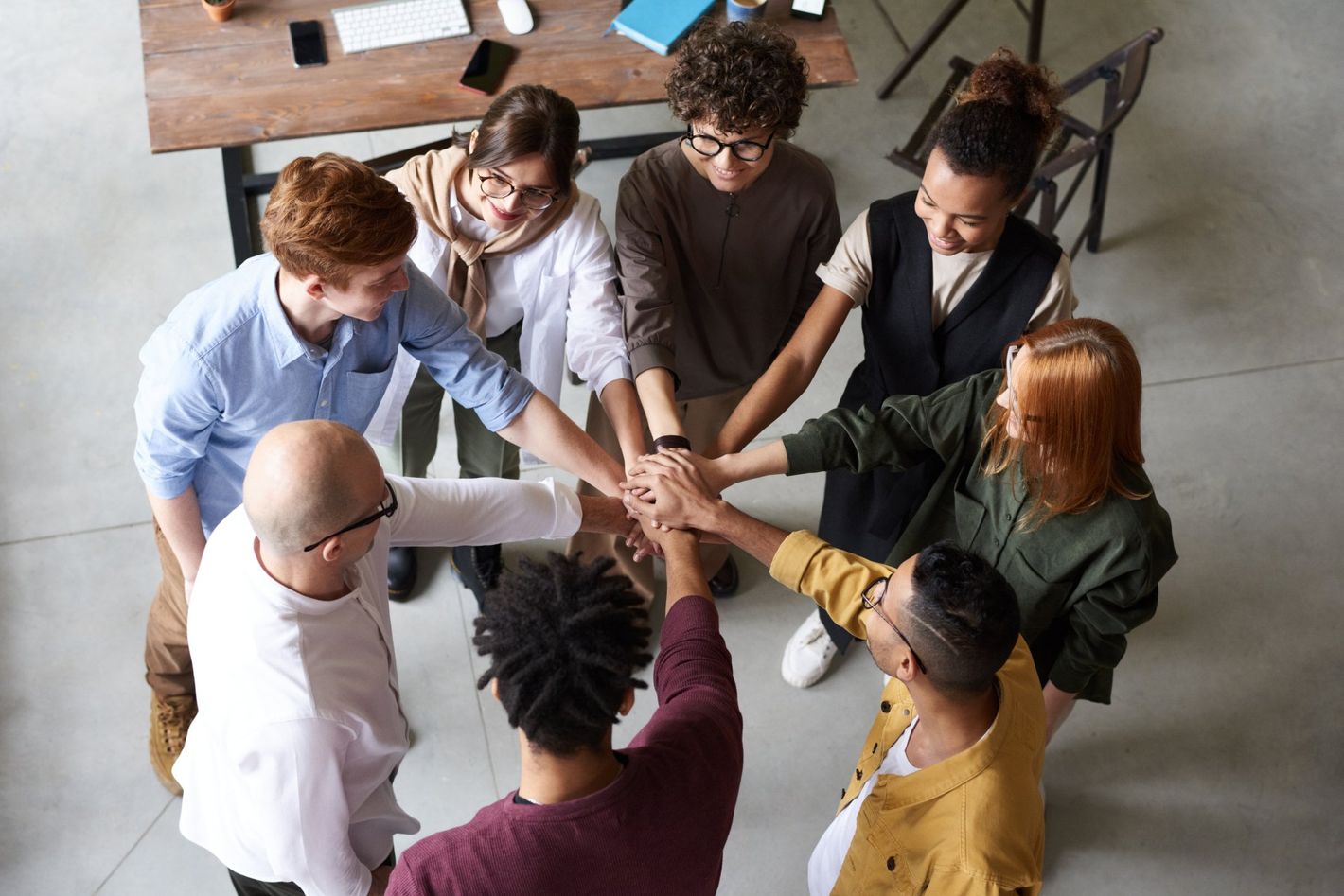 a group of people are putting their hands together in a circle because of the workshops and Facilitator Training