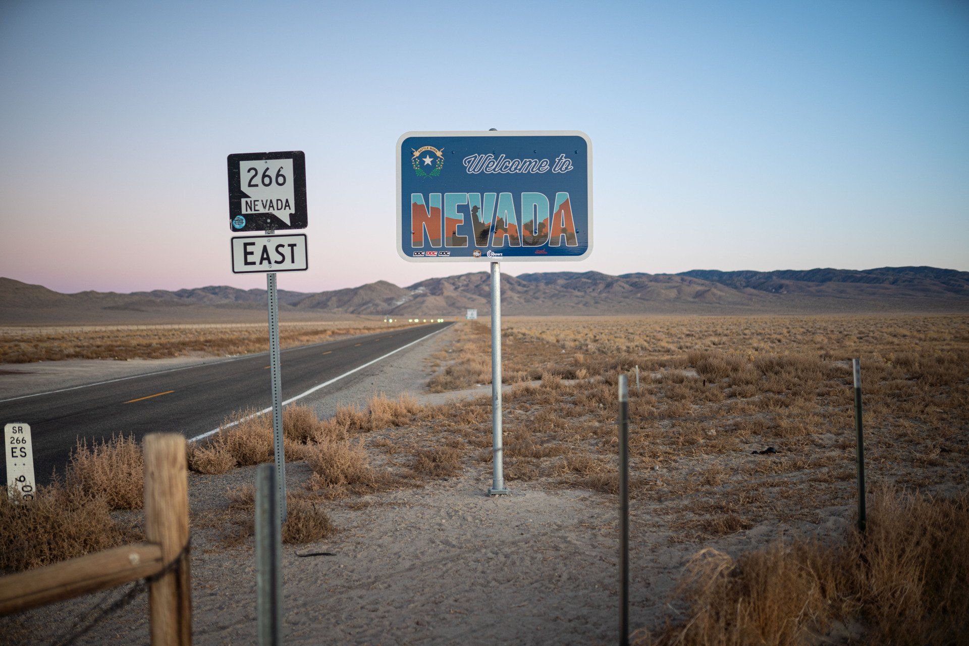 A sign that says welcome to nevada is on the side of a road.