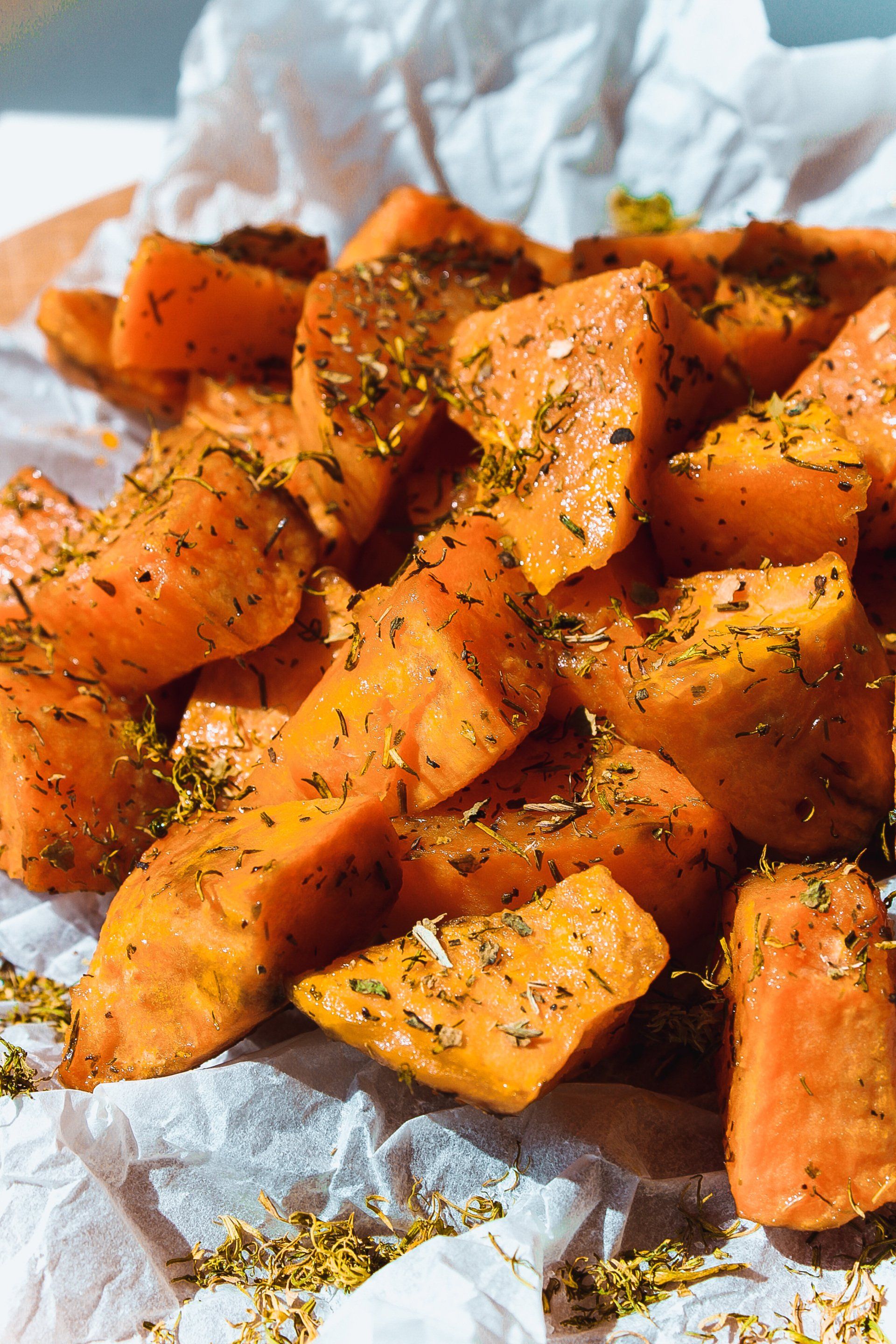 A close up of a pile of sweet potatoes with herbs on a plate.