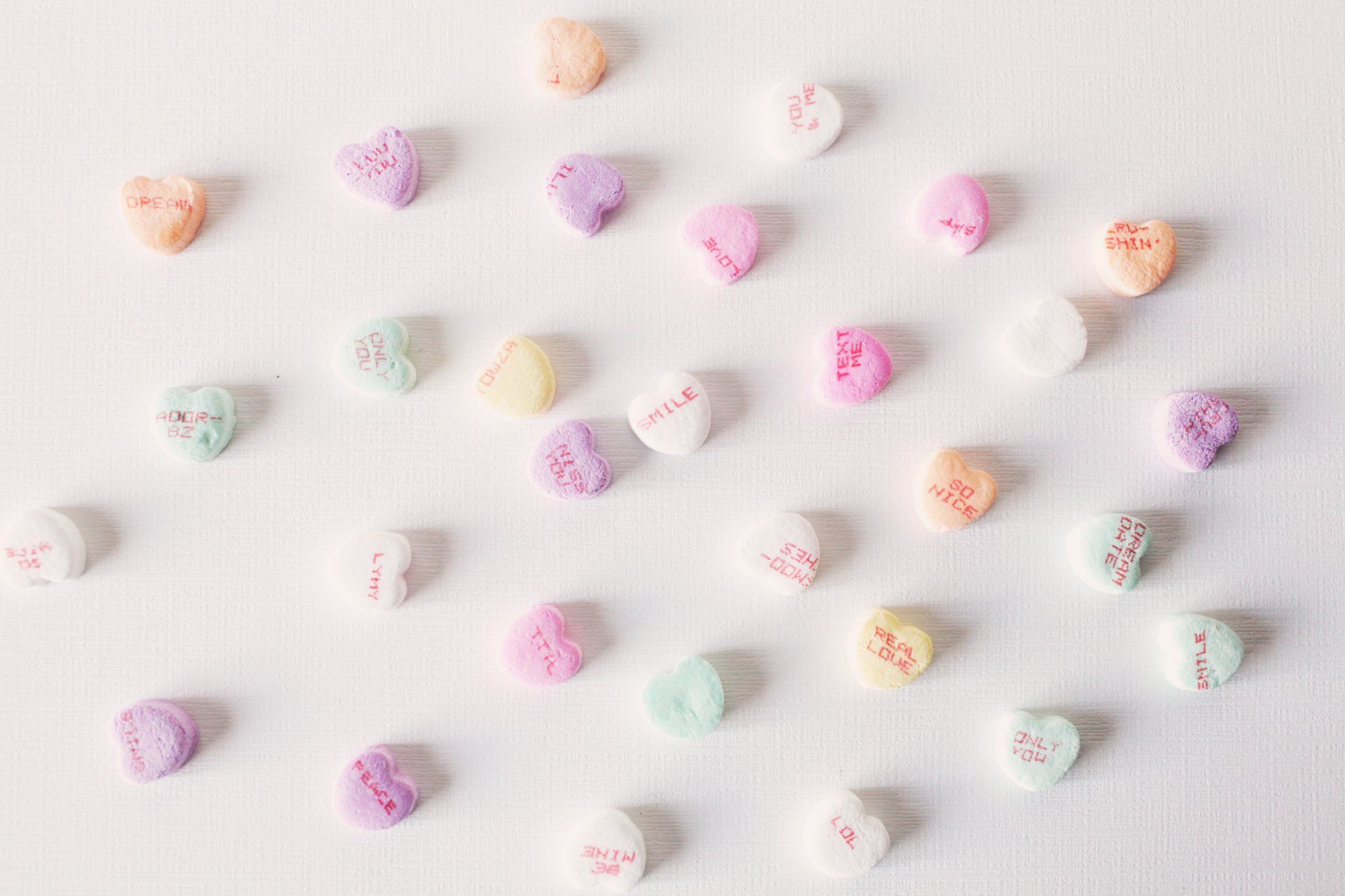 Multicolored heart-shaped Valentine's Day candies spread out on a white table