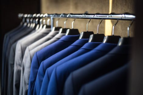 Row of blue and gray dress shirts hanging on a closet rack