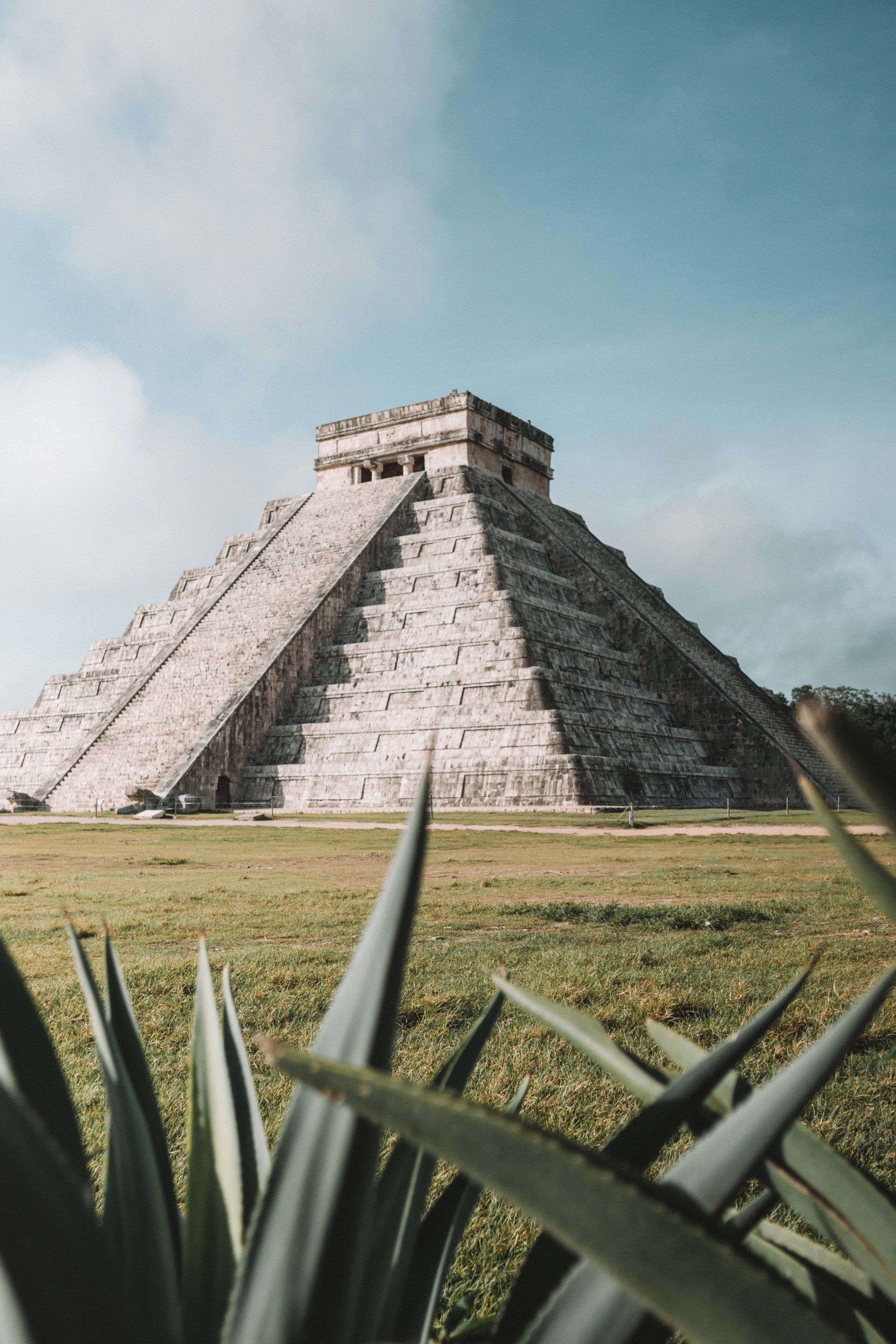 A large pyramid is sitting in the middle of a grassy field.