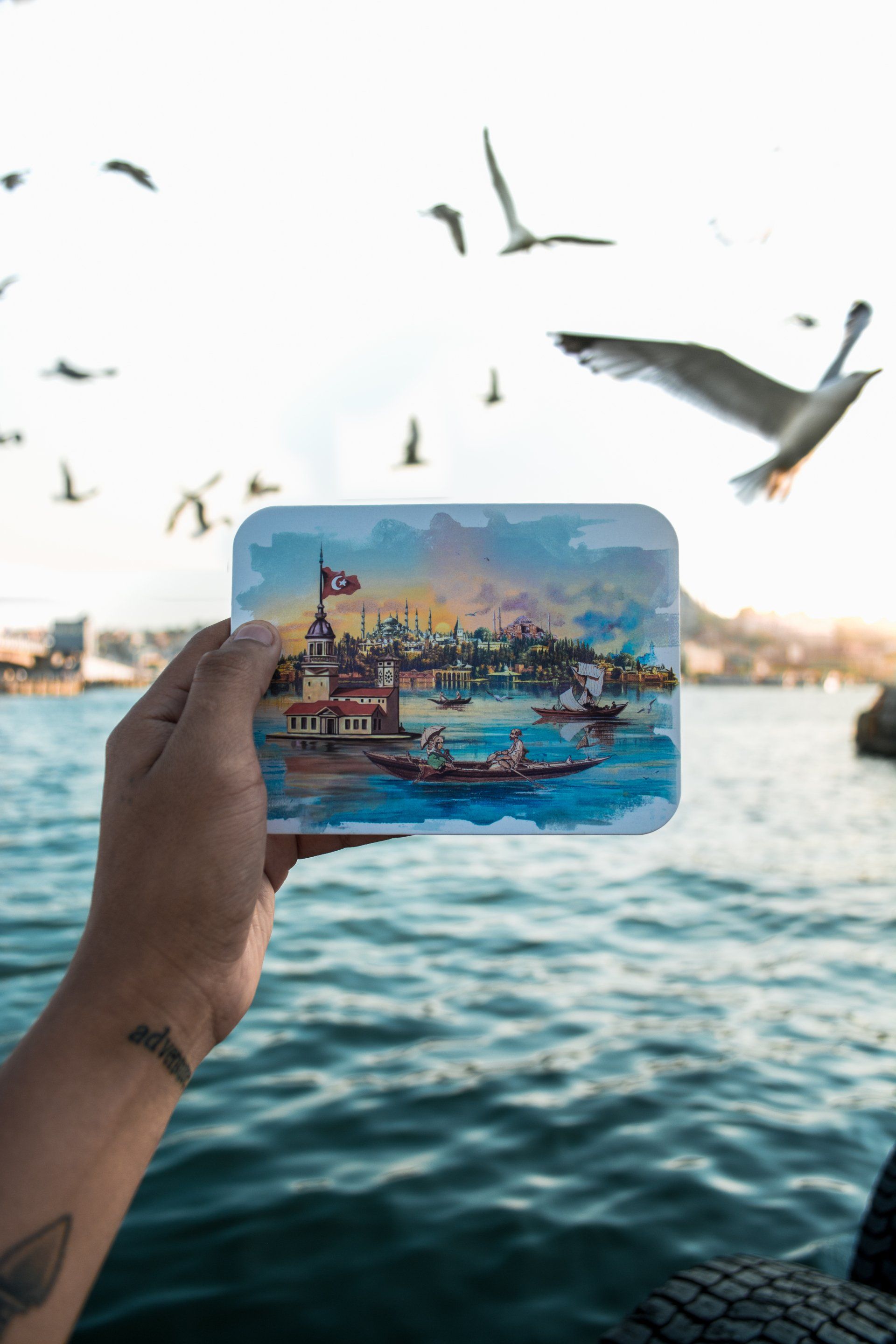 A person is holding a picture of a boat in the water.