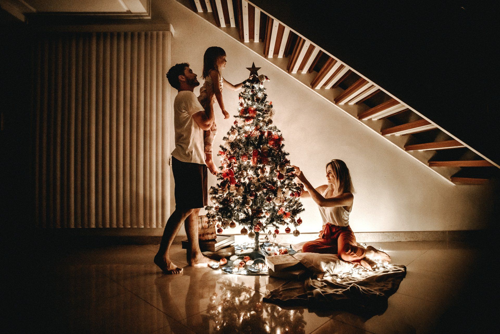 A family is decorating a christmas tree in a living room.